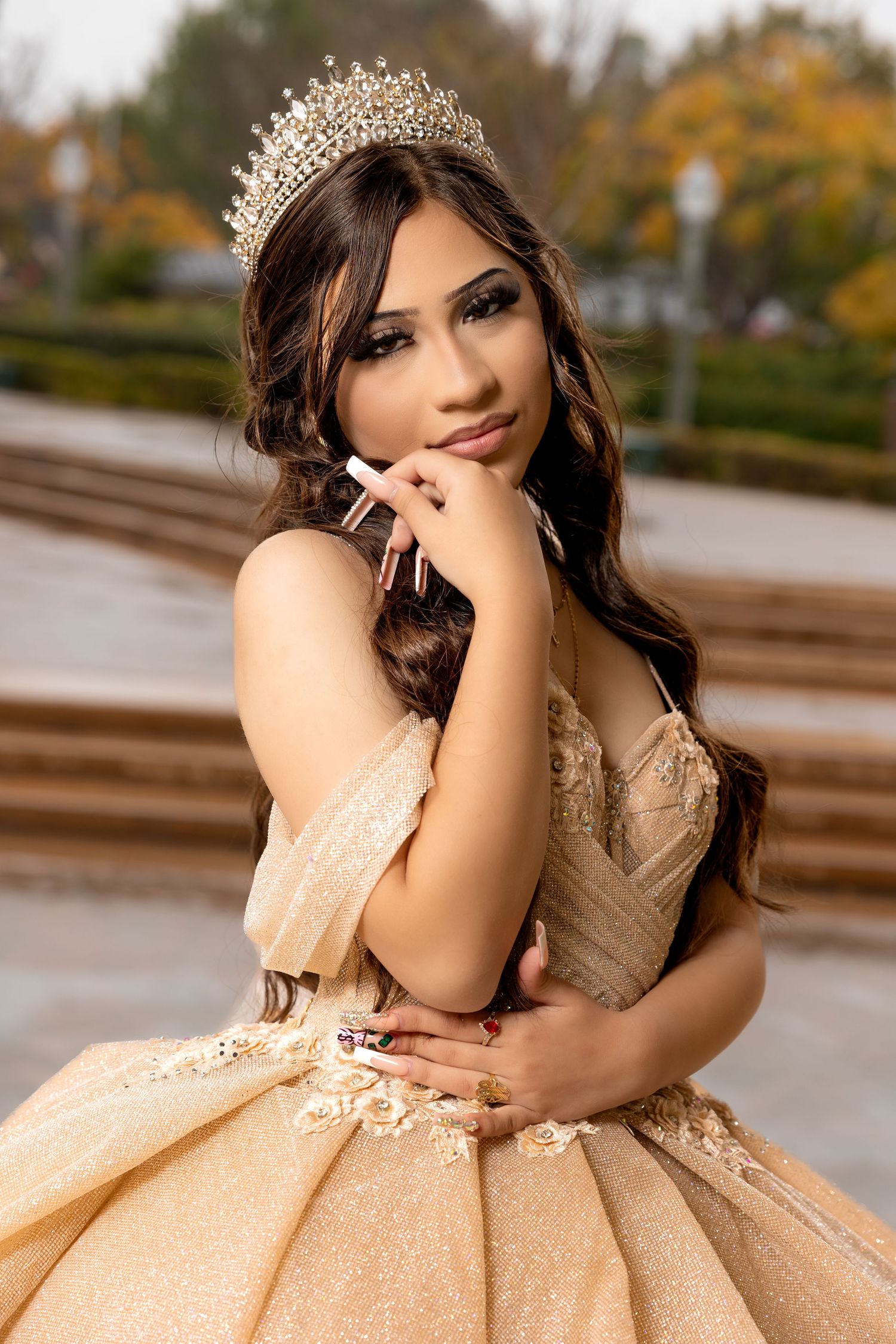 An autumnal outdoor portrait featuring a sparkly champagne ball gown and crystal crown.