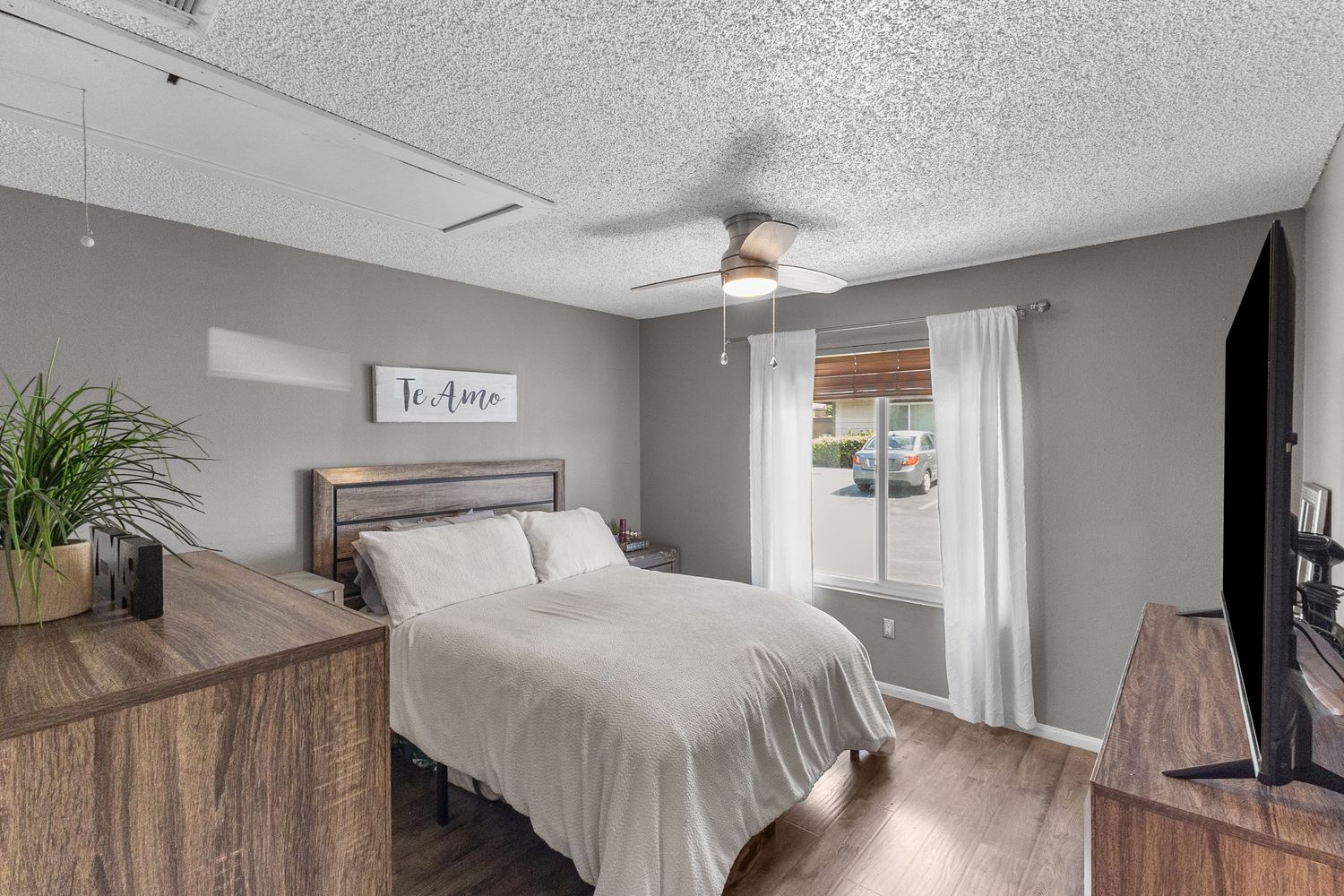 Cozy bedroom with neutral decor, ceiling fan, and natural lighting.