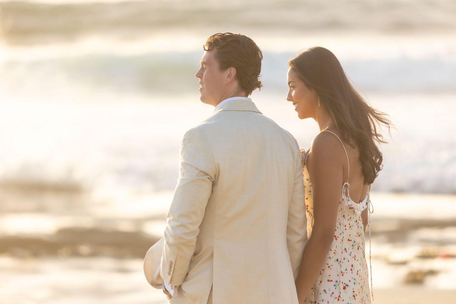 Candid engagement photography session on sandy beach at dusk.