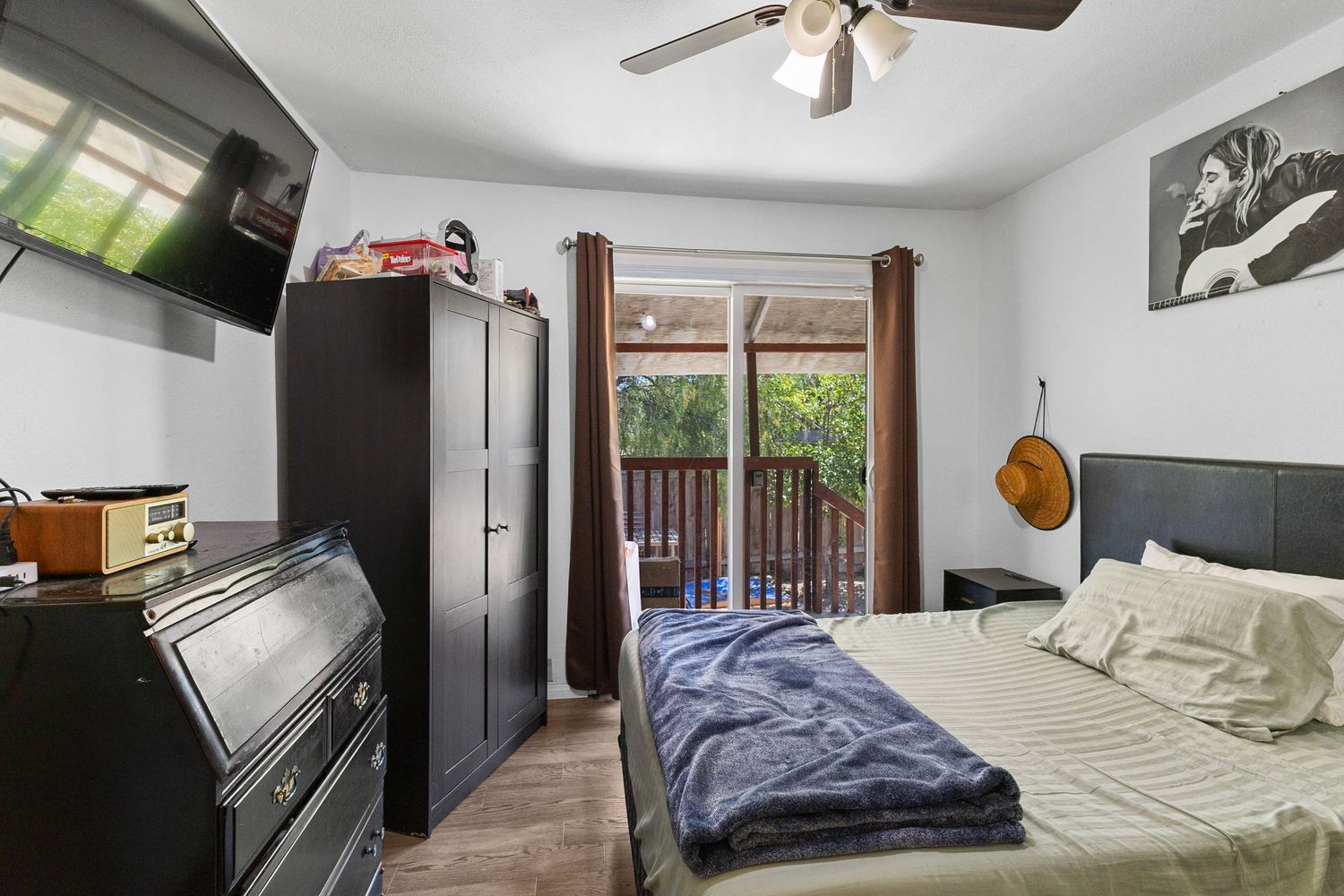 Bedroom with ceiling fan, window, and gray bedding in neutral tones.