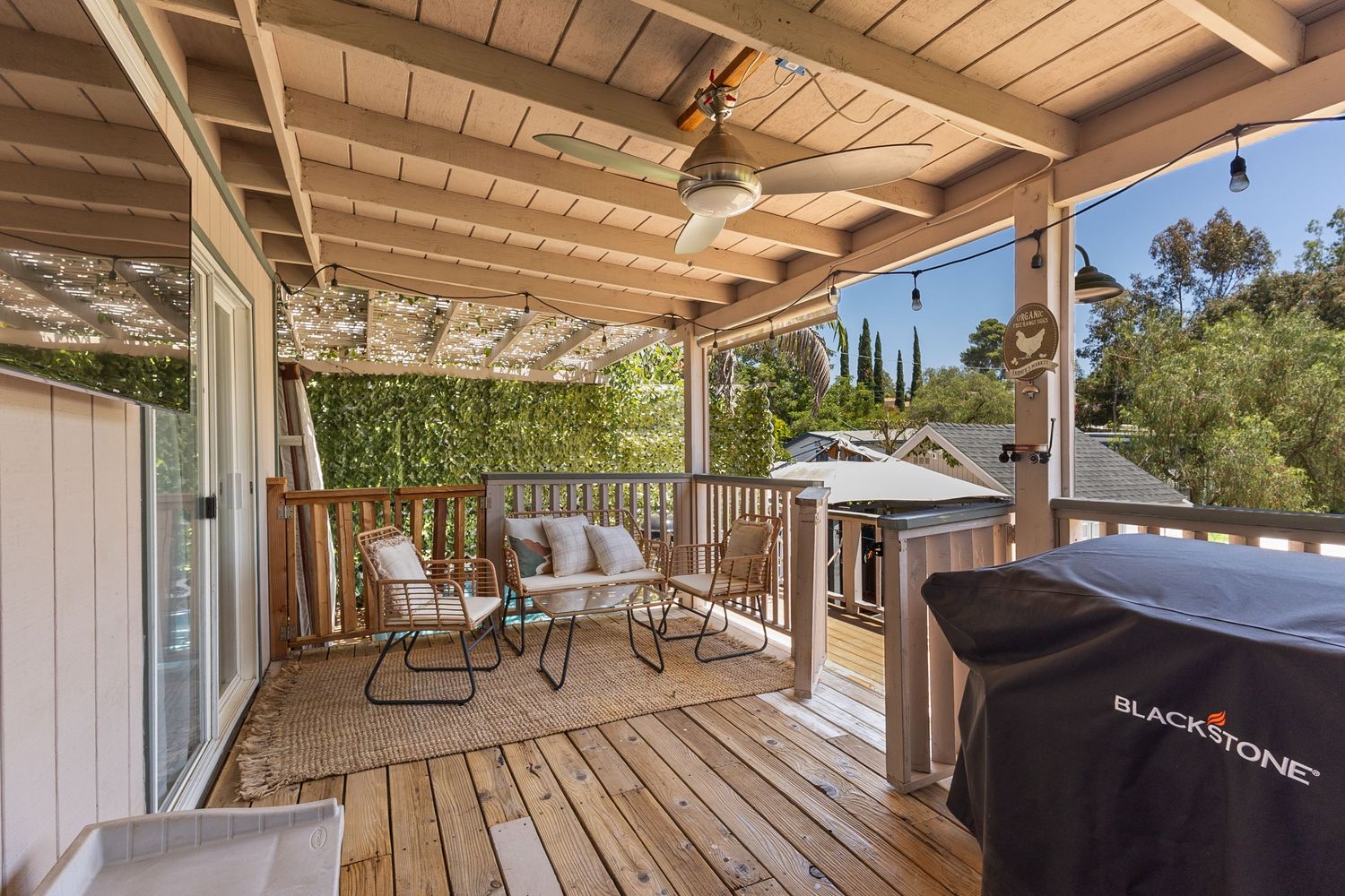 Covered outdoor patio with wooden ceiling beams and seating area.