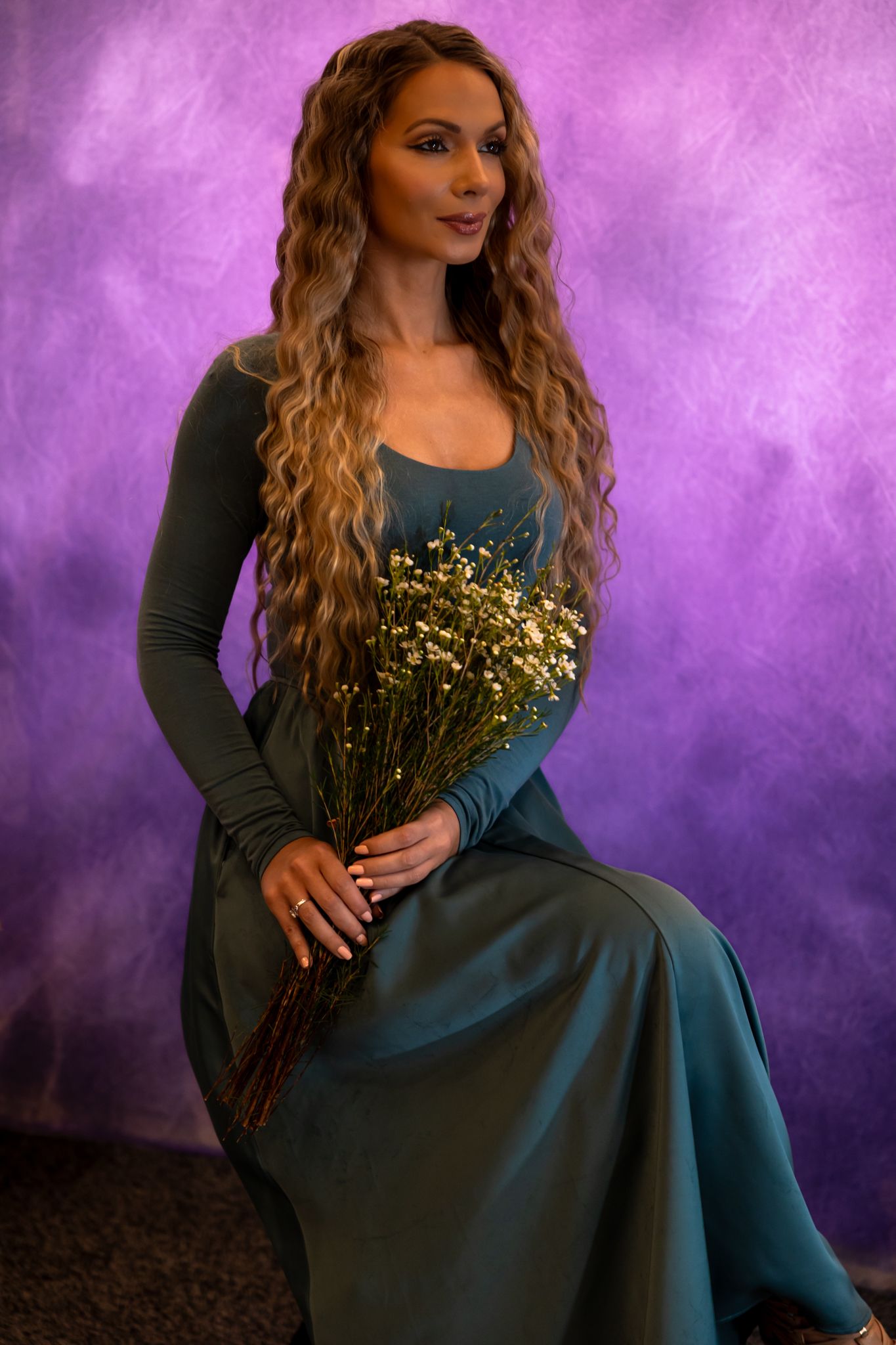 Fashion photoshoot featuring a teal dress with gold sequin details against a purple backdrop.