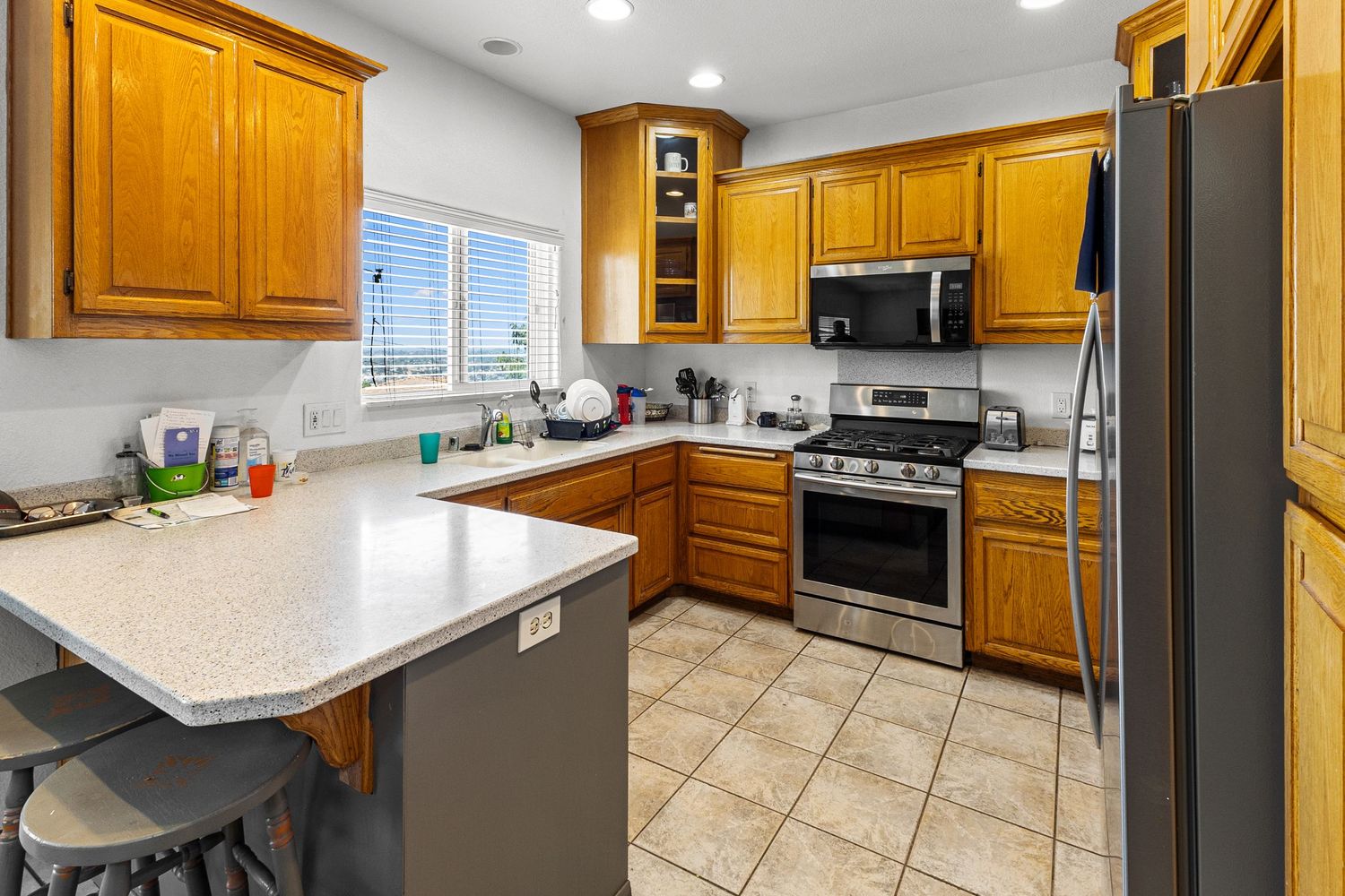 Spacious kitchen with honey oak cabinets, tile flooring, and light granite countertops.