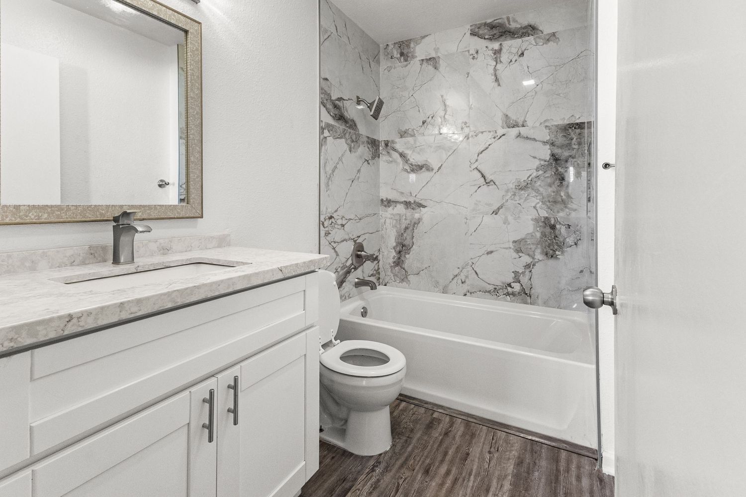 Clean white bathroom featuring quartz countertops, modern fixtures, and subway tile backsplash.
