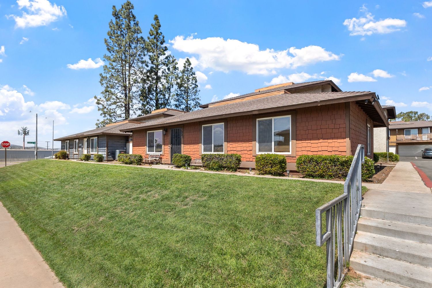 Residential exterior view showing ranch-style homes on a grassy hillside under blue skies.