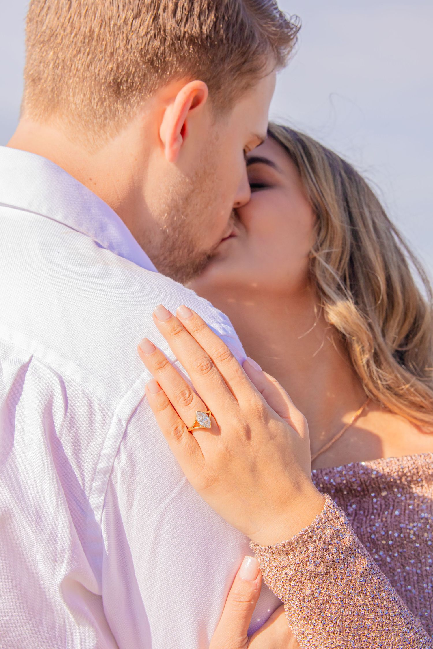 Close up shot of an intimate moment showing a sparkling engagement ring on the beach.