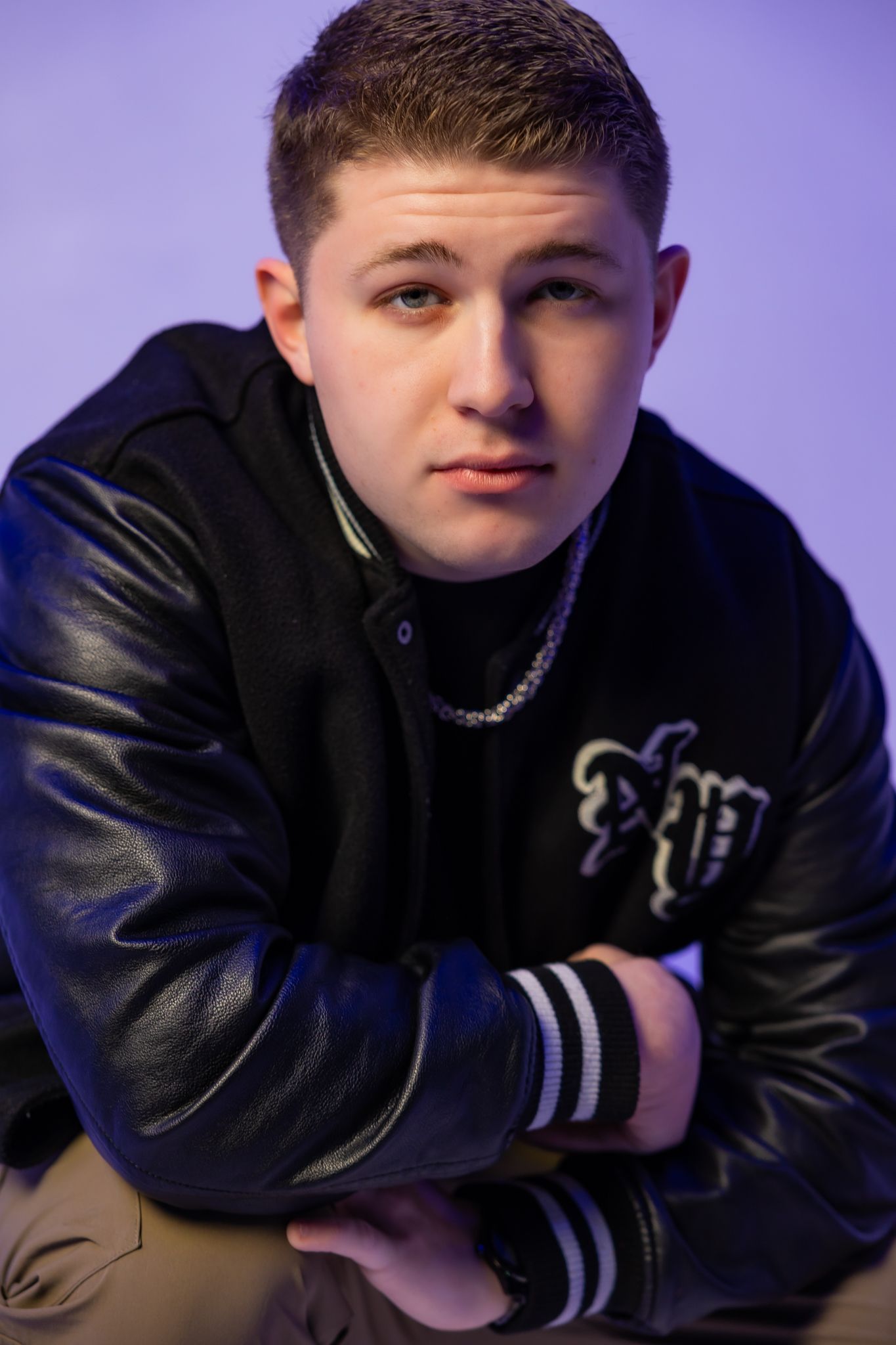 Studio portraits of person in black leather jacket against purple lighting setup.