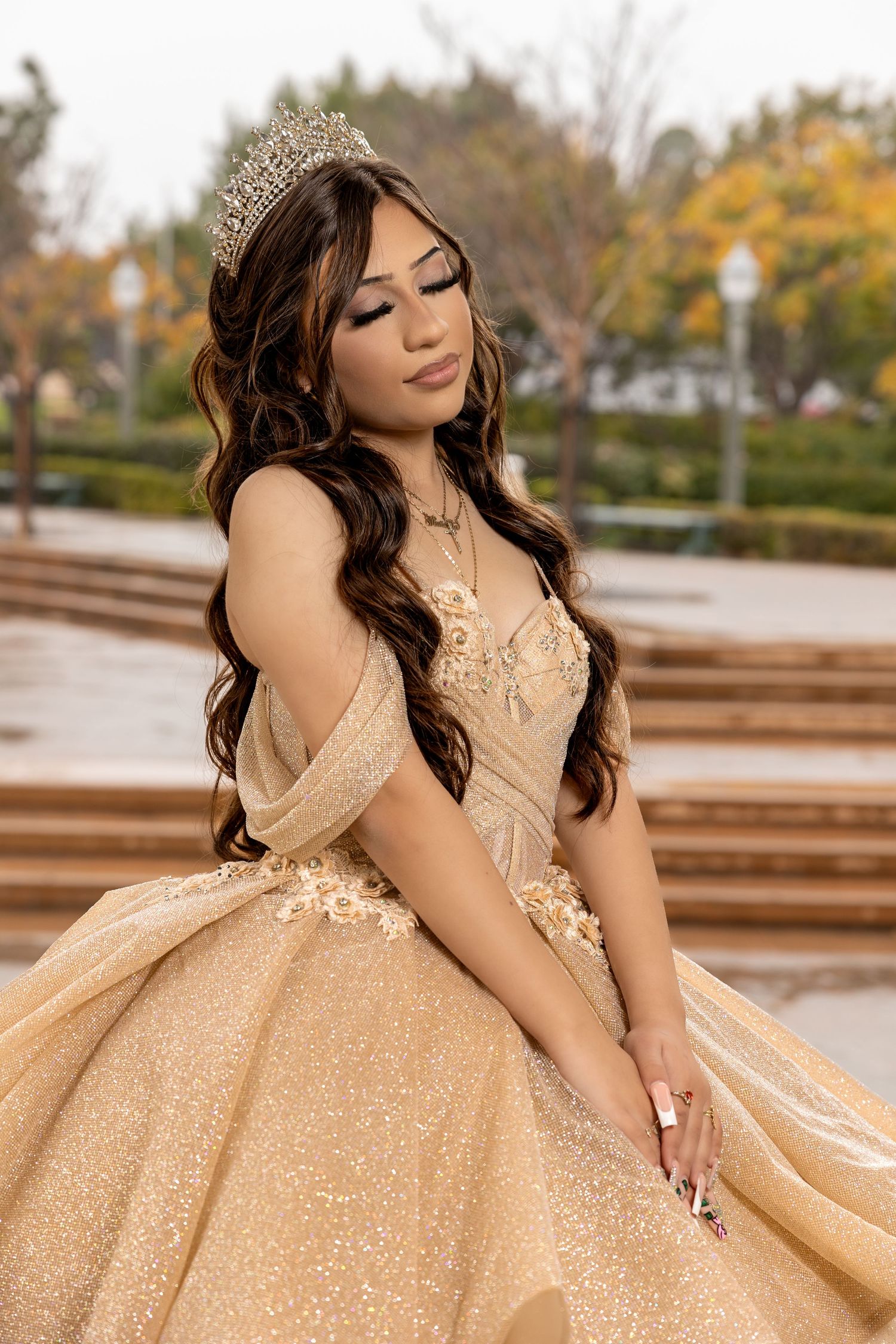 Elegant champagne-colored quinceañera dress with sequins and beading shown in an outdoor setting.