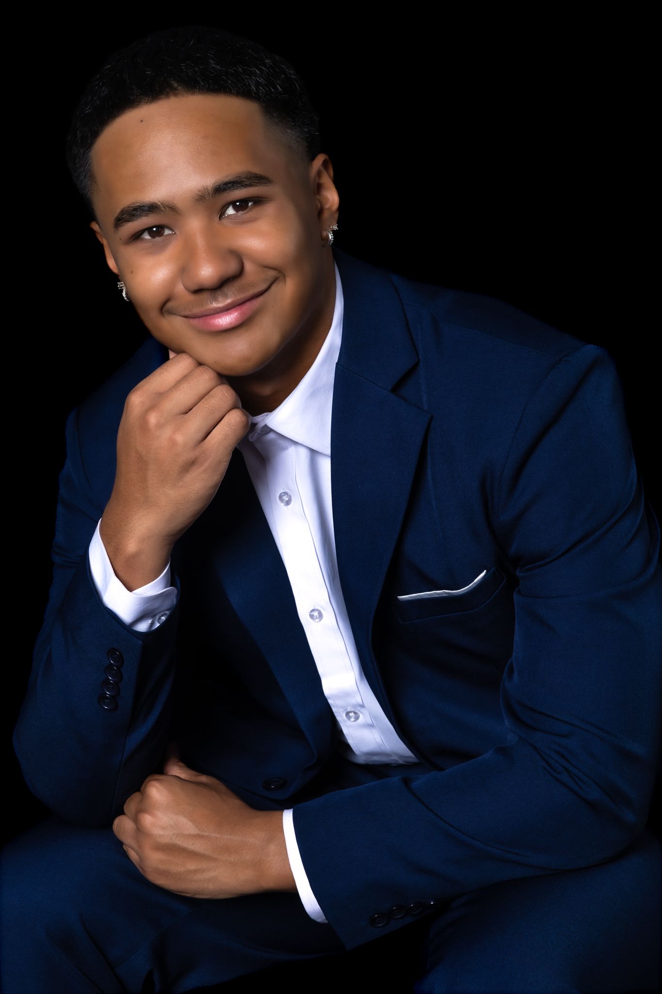 Professional portrait series showing person in navy blue suit and white shirt against dark background making expressive poses.