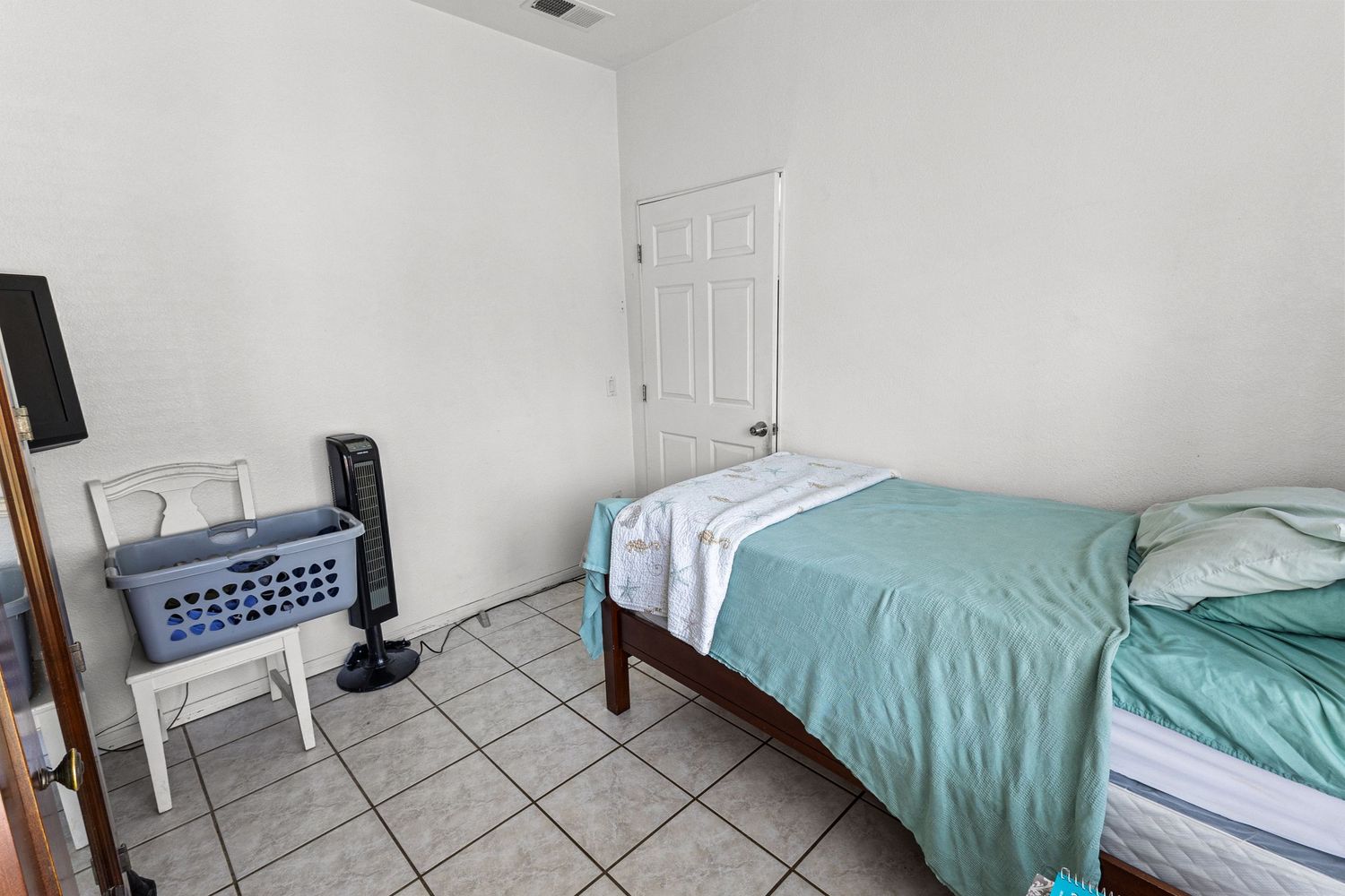Bedroom with tiled flooring and mint green bedding in minimalist design.