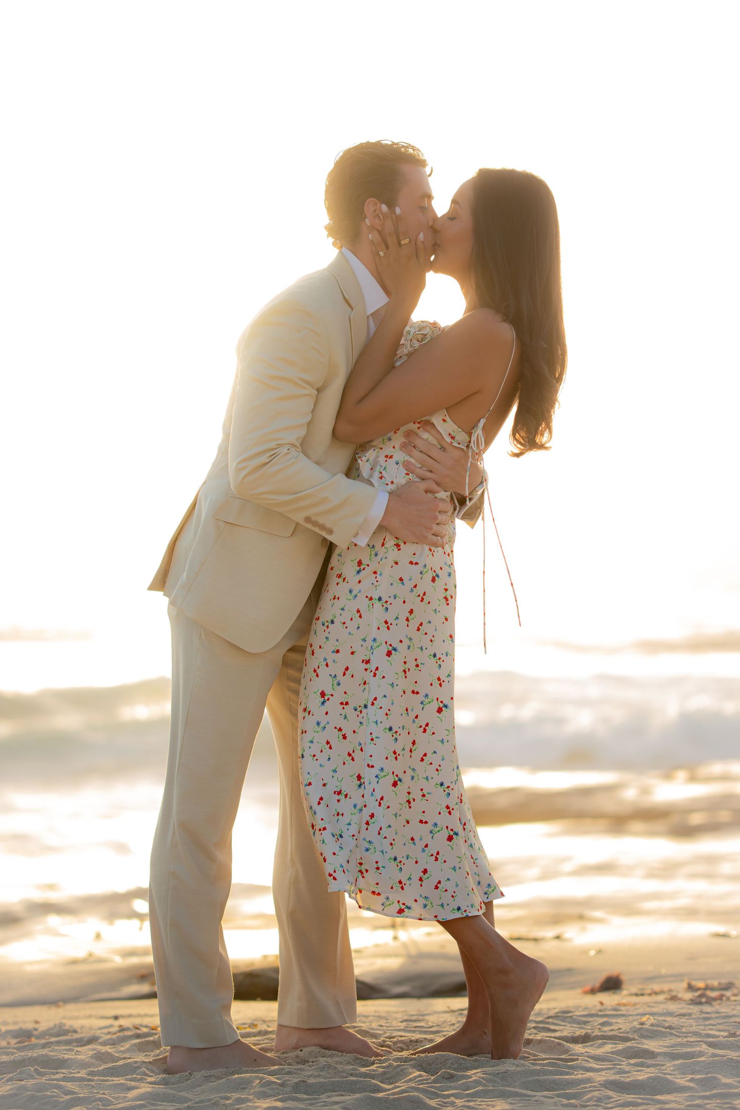Romantic beach proposal scene at sunset with waves crashing in the background.