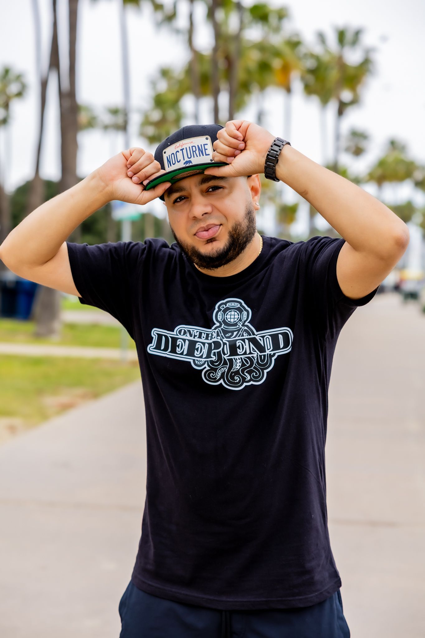 Several shots of person wearing black t-shirt with Defend logo against palm tree backdrop.