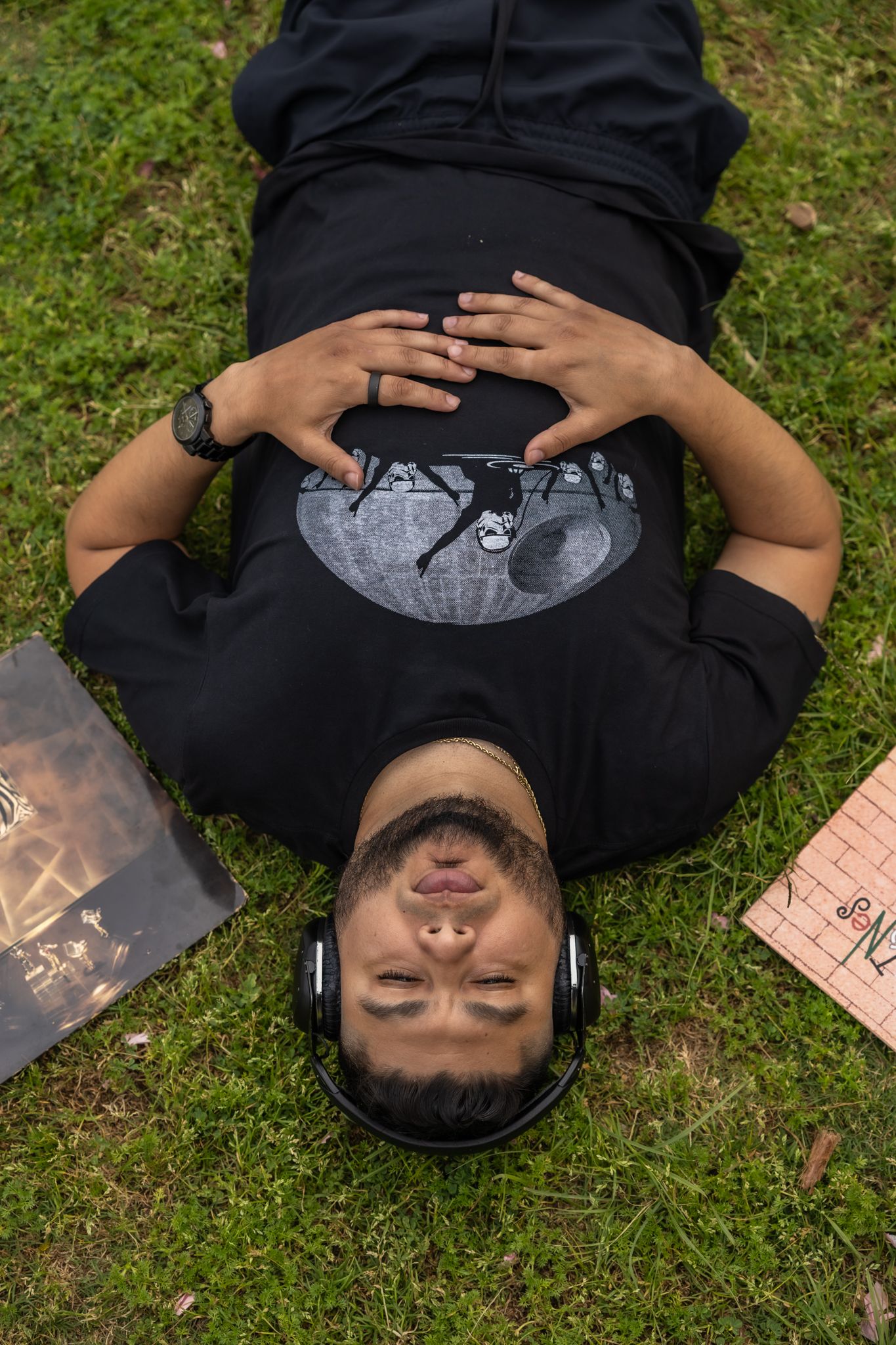 Person lying on grass wearing dark clothing in artistic photo series.