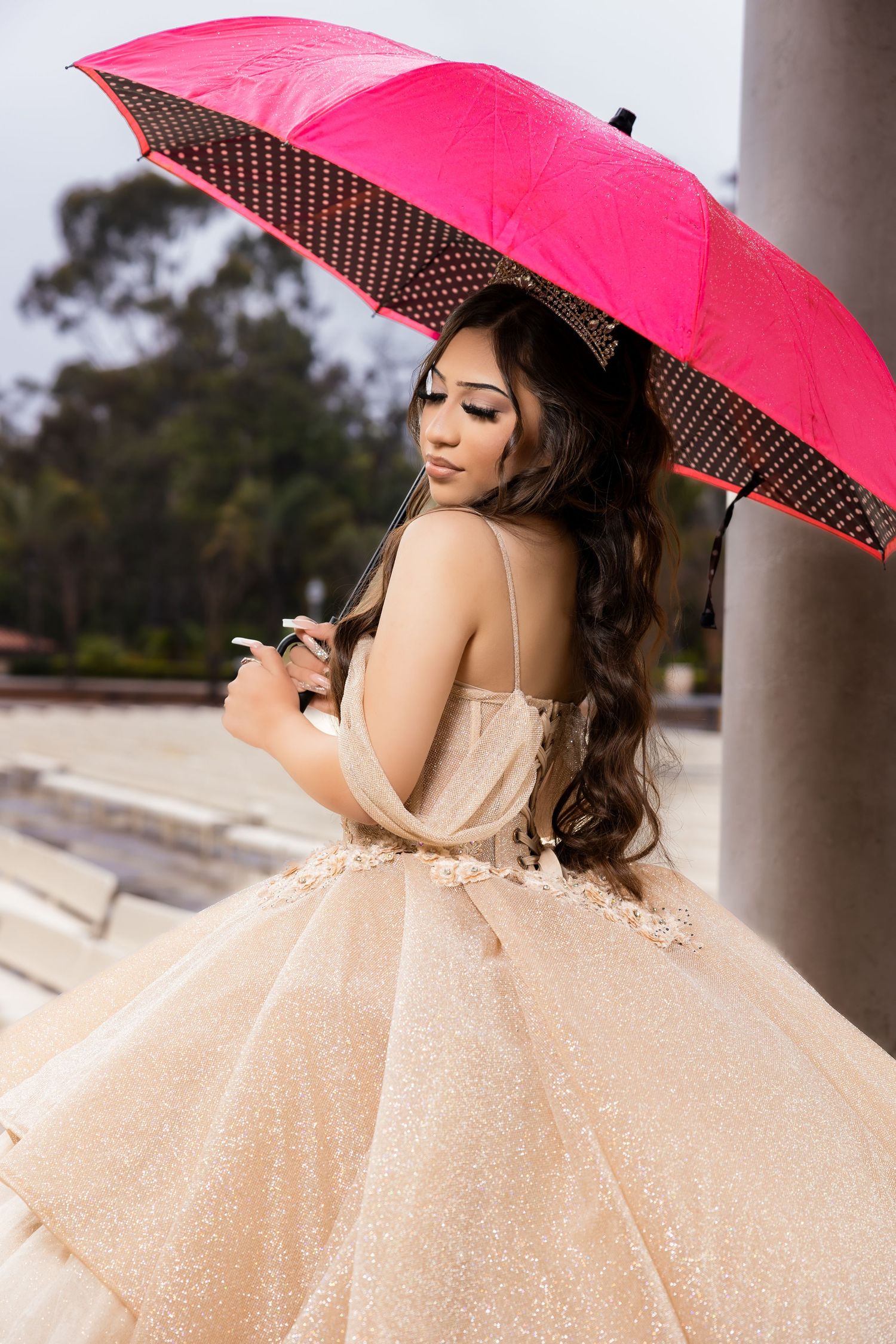 Stunning ball gown with pink umbrella photographed against classical architecture.