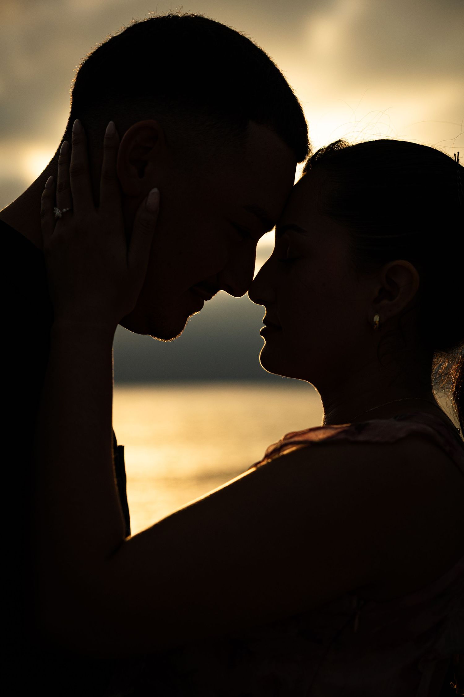 Romantic silhouette of a couple in an intimate moment against a golden sunset background.