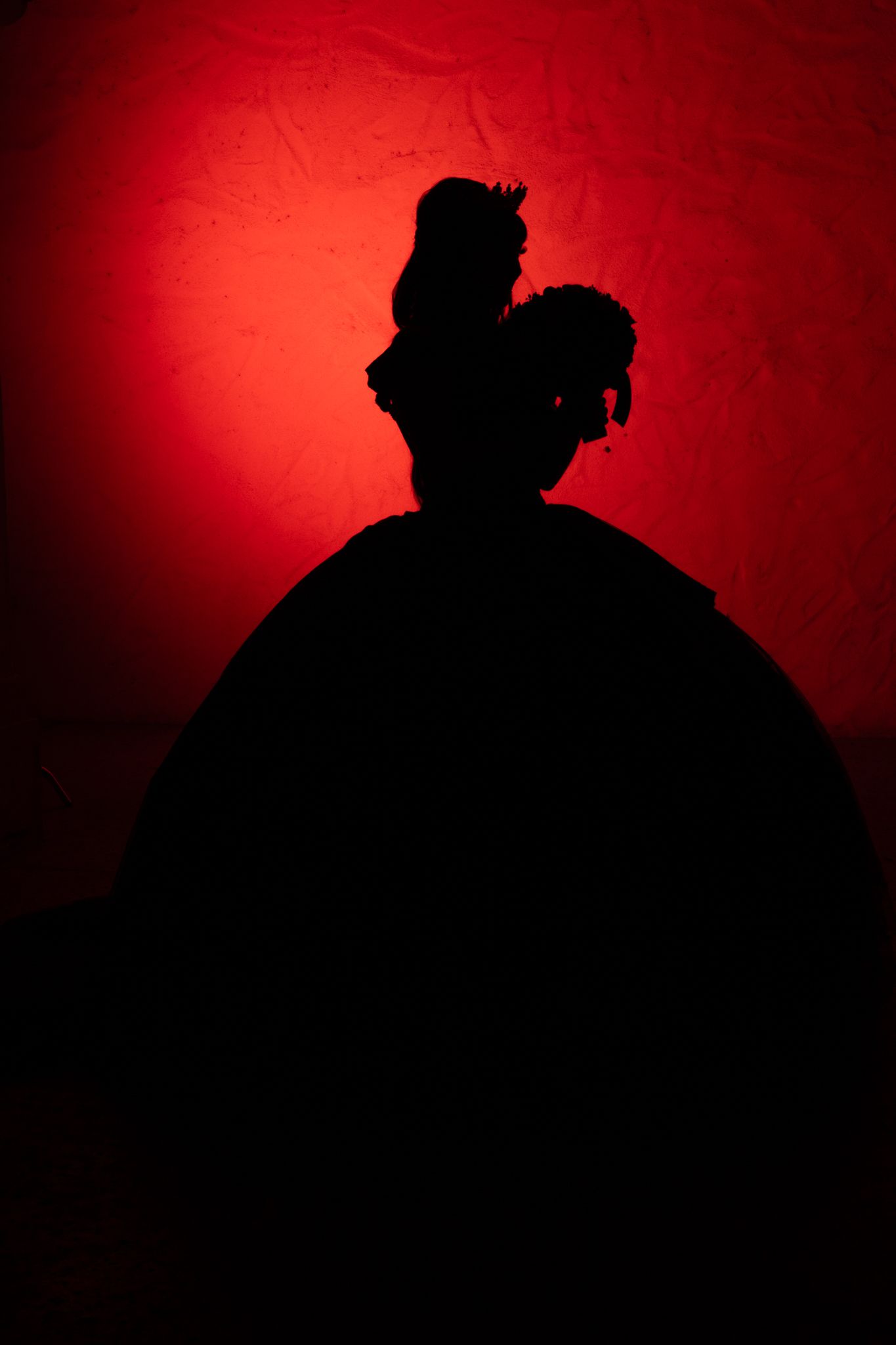 A silhouette of a ballgown against a deep red background creates a dramatic contrast.