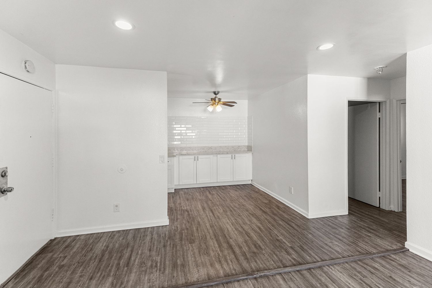 Empty hallway with recessed lighting showcasing modern vinyl flooring and white walls.