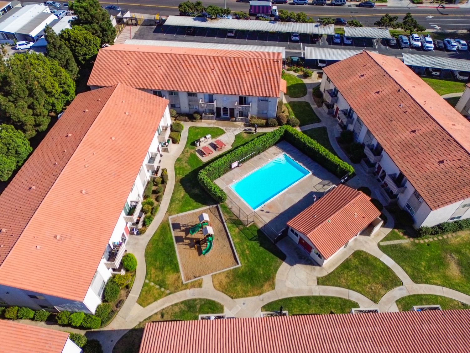 Aerial view of residential complex with red tile roofs and community swimming pool.