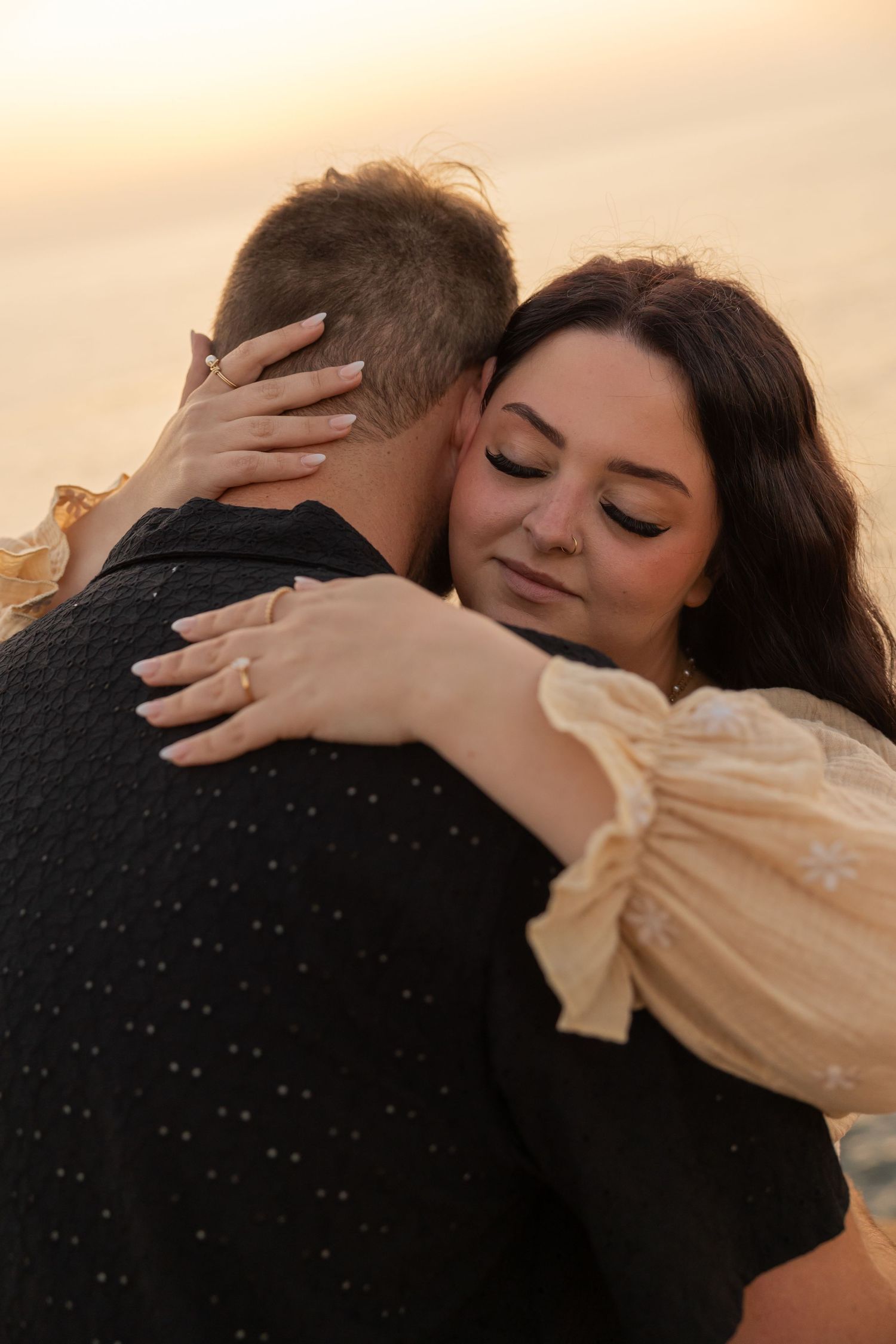 Intimate embrace captured during golden hour showing a ring and romantic moment.