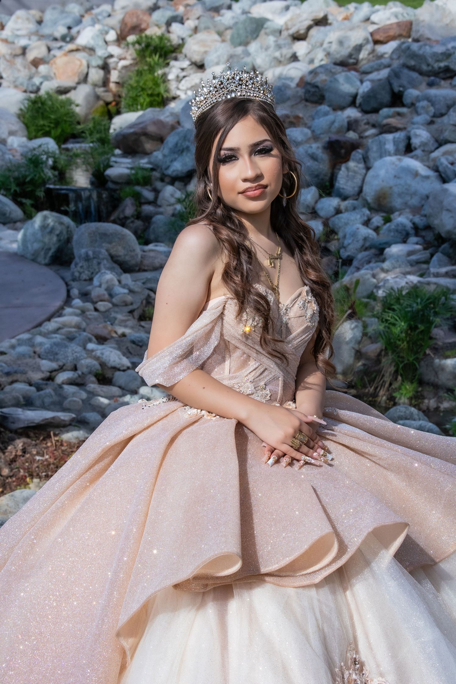 A princess-style portrait with a glittering ball gown against a rocky natural backdrop.