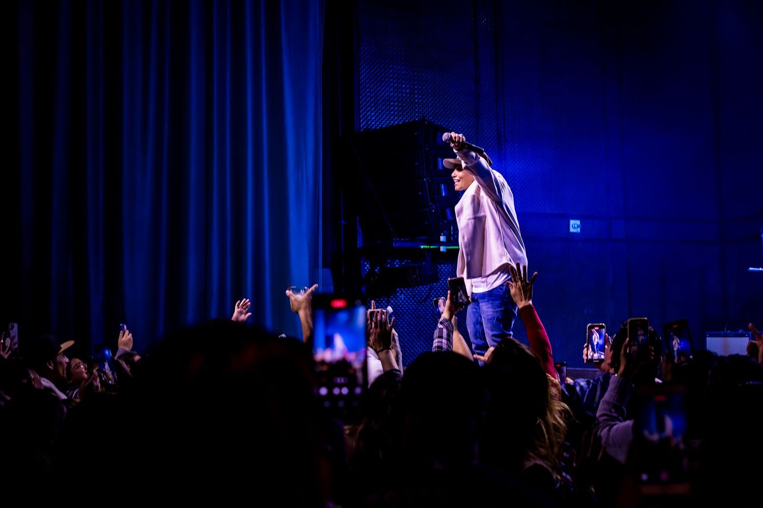 Concert venue with blue stage lighting and silhouetted audience members.