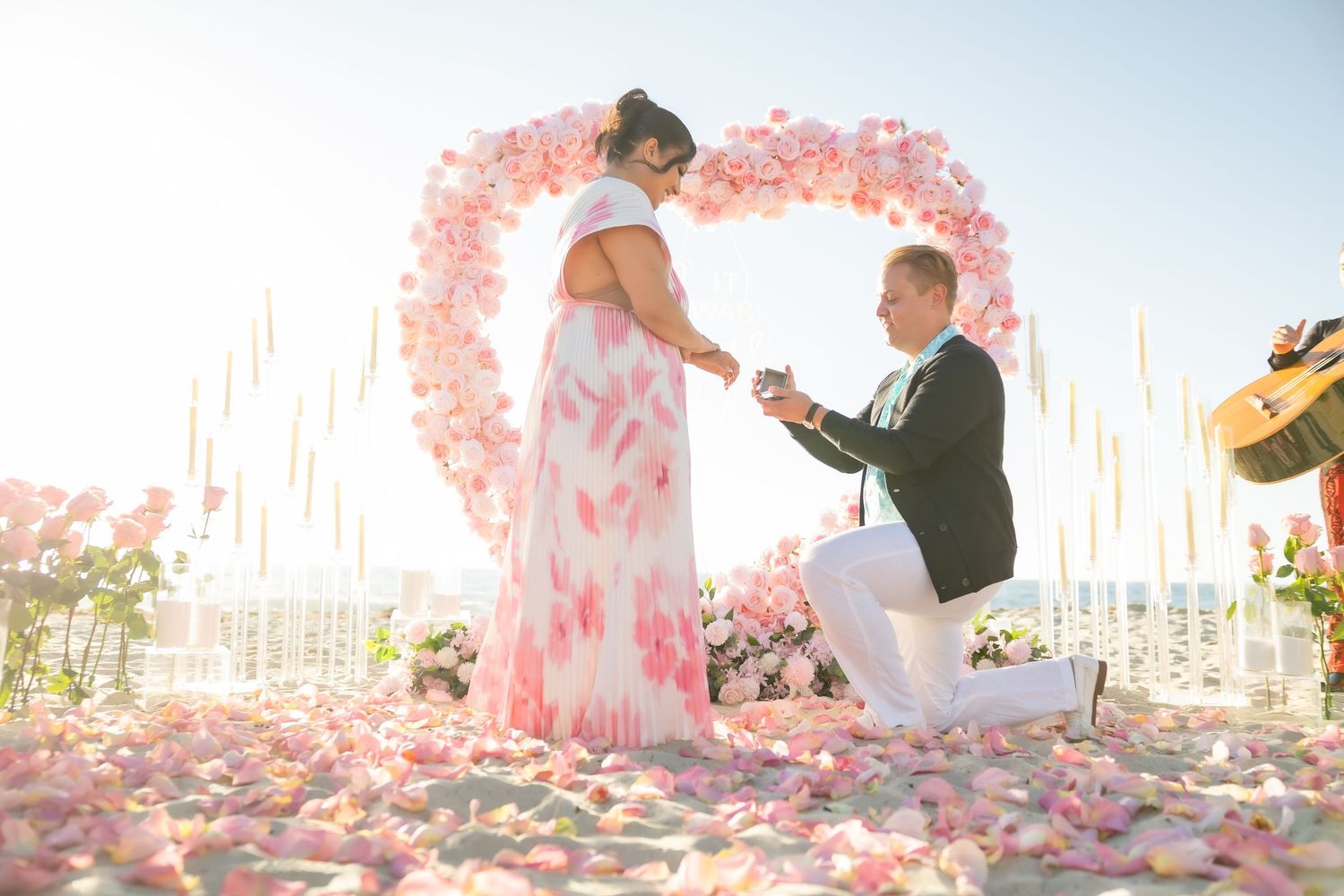 Pink floral arch setup on a beachfront during a romantic event.