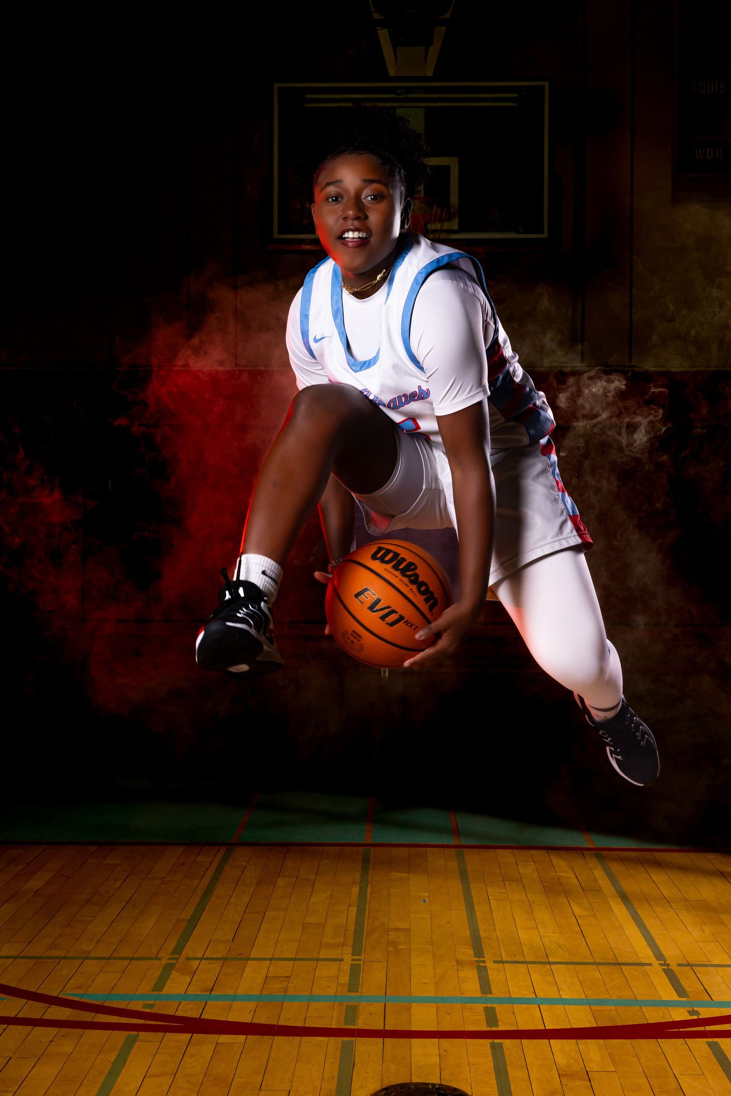 Dynamic basketball photoshoot on indoor court with dramatic lighting and smoke effects.