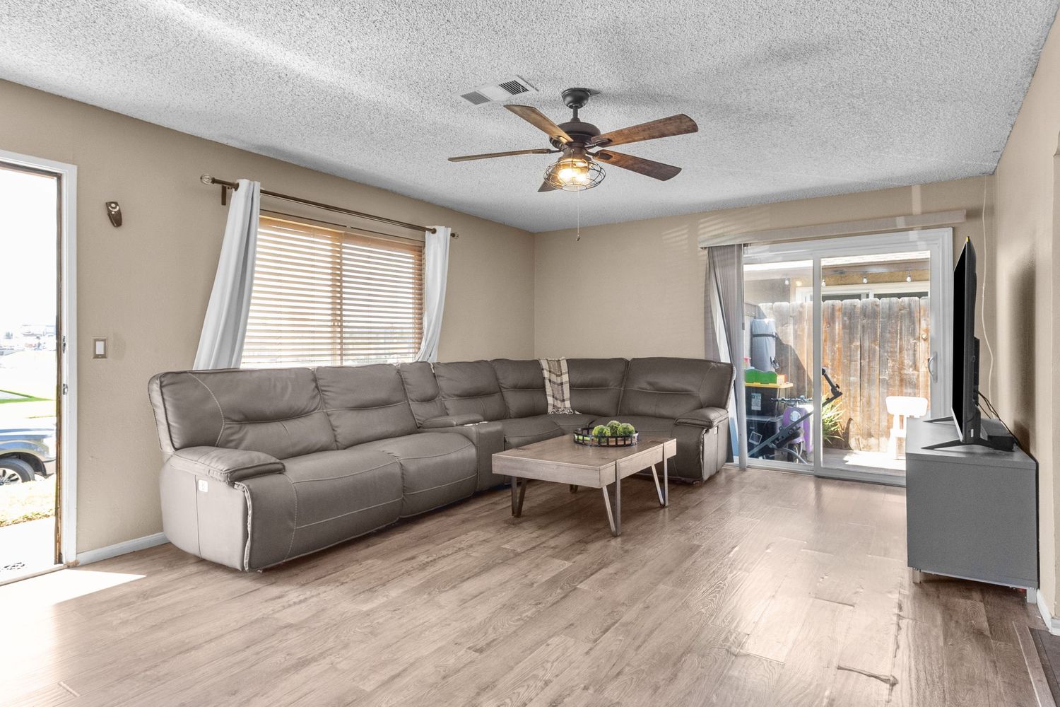 Open concept living space with gray sectional sofa and laminate flooring.