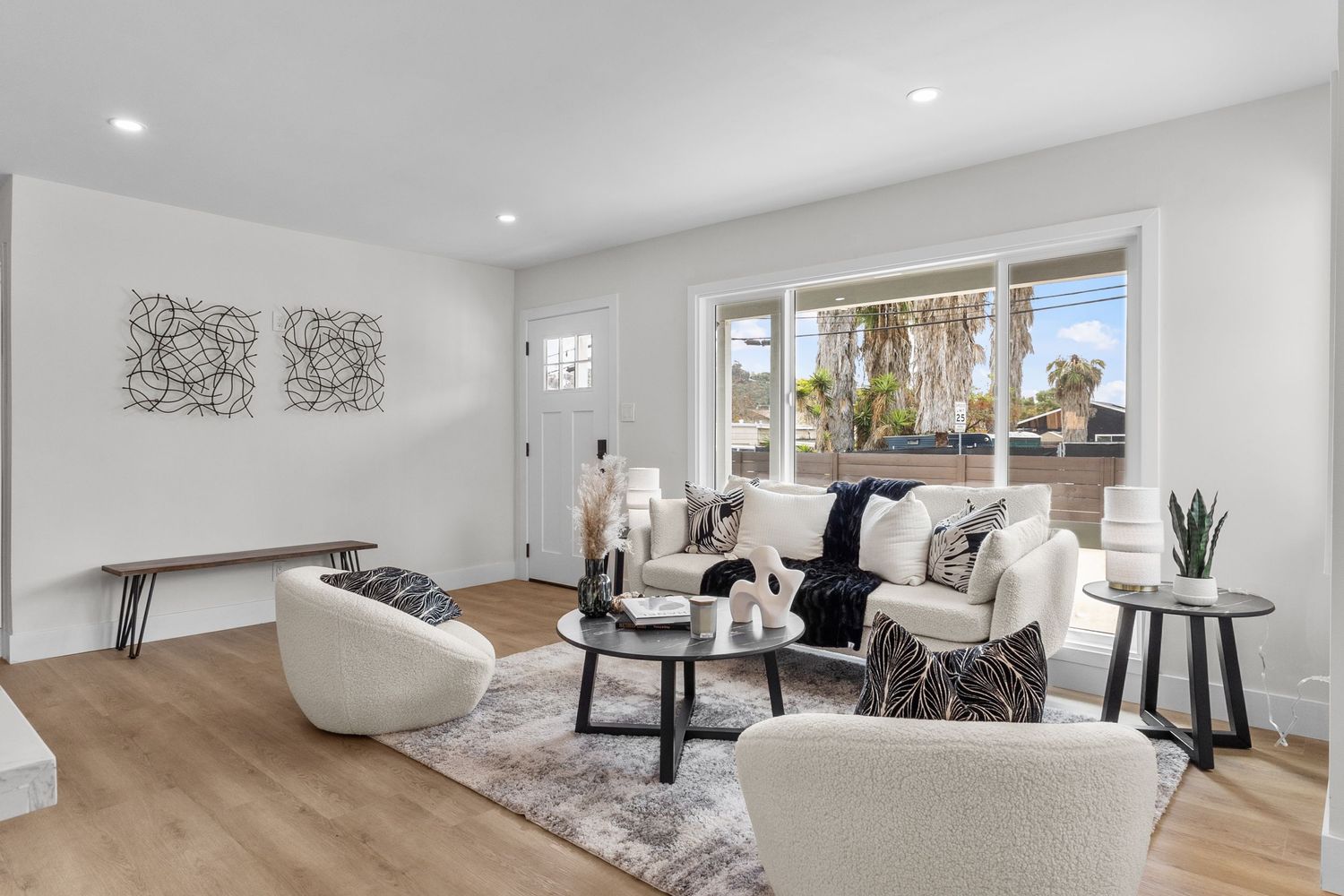 Bright white living room with minimalist furniture and large windows providing natural light.