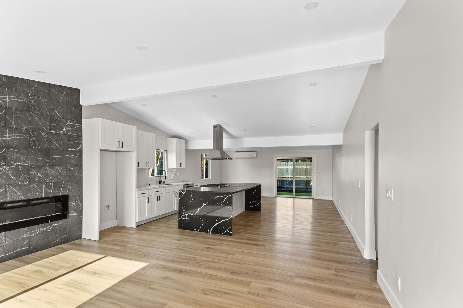 Modern empty room interior with wooden floors and white walls featuring natural lighting.