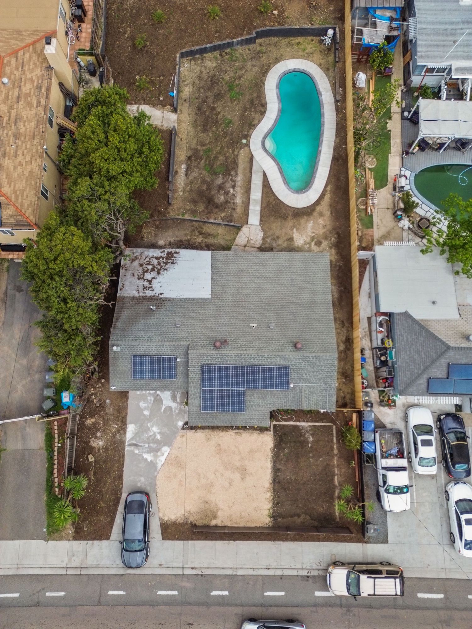 Aerial view showing residential properties with swimming pools and solar panels.