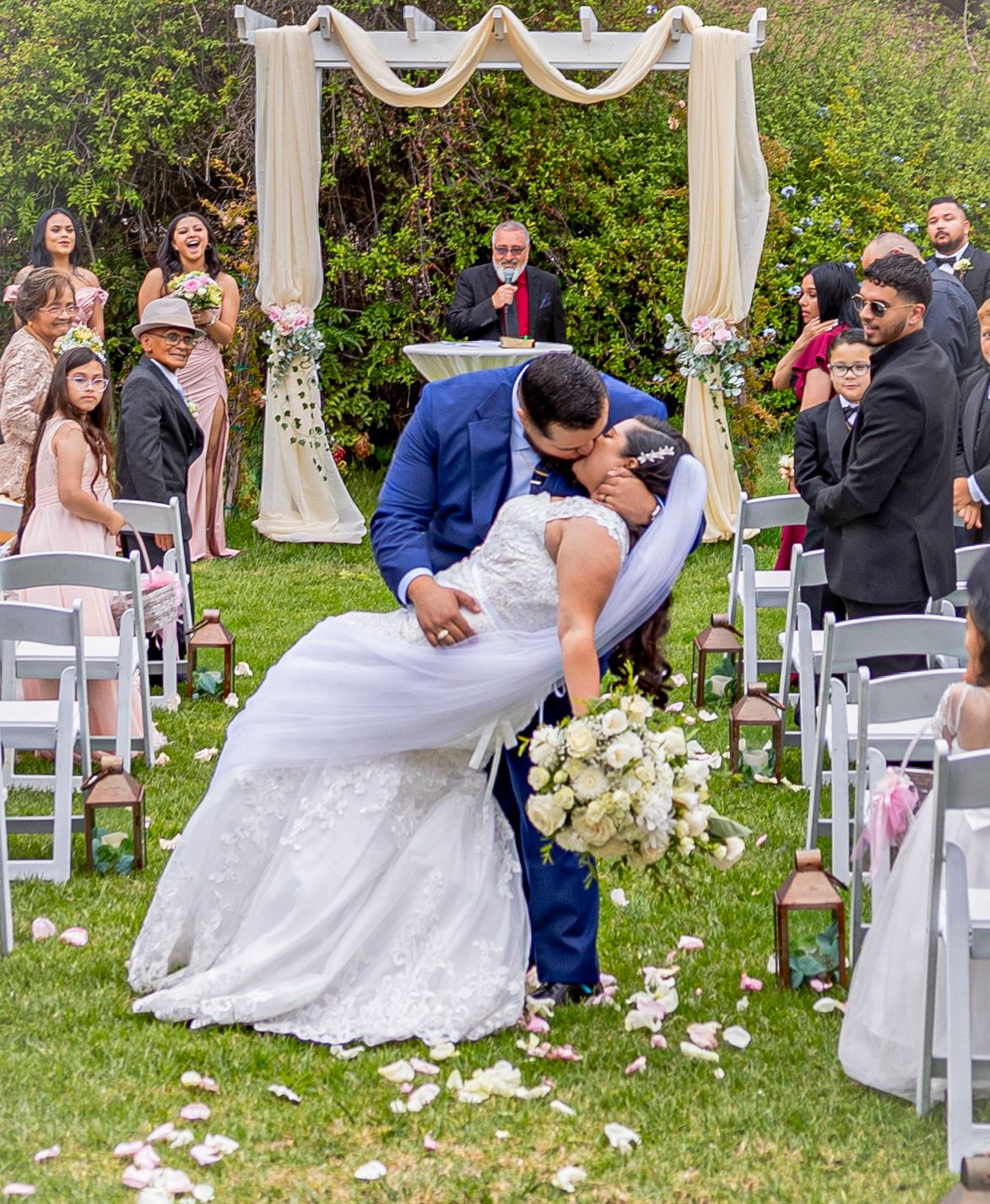 Outdoor wedding ceremony setup with white chairs and floral decorations under an elegant arch.