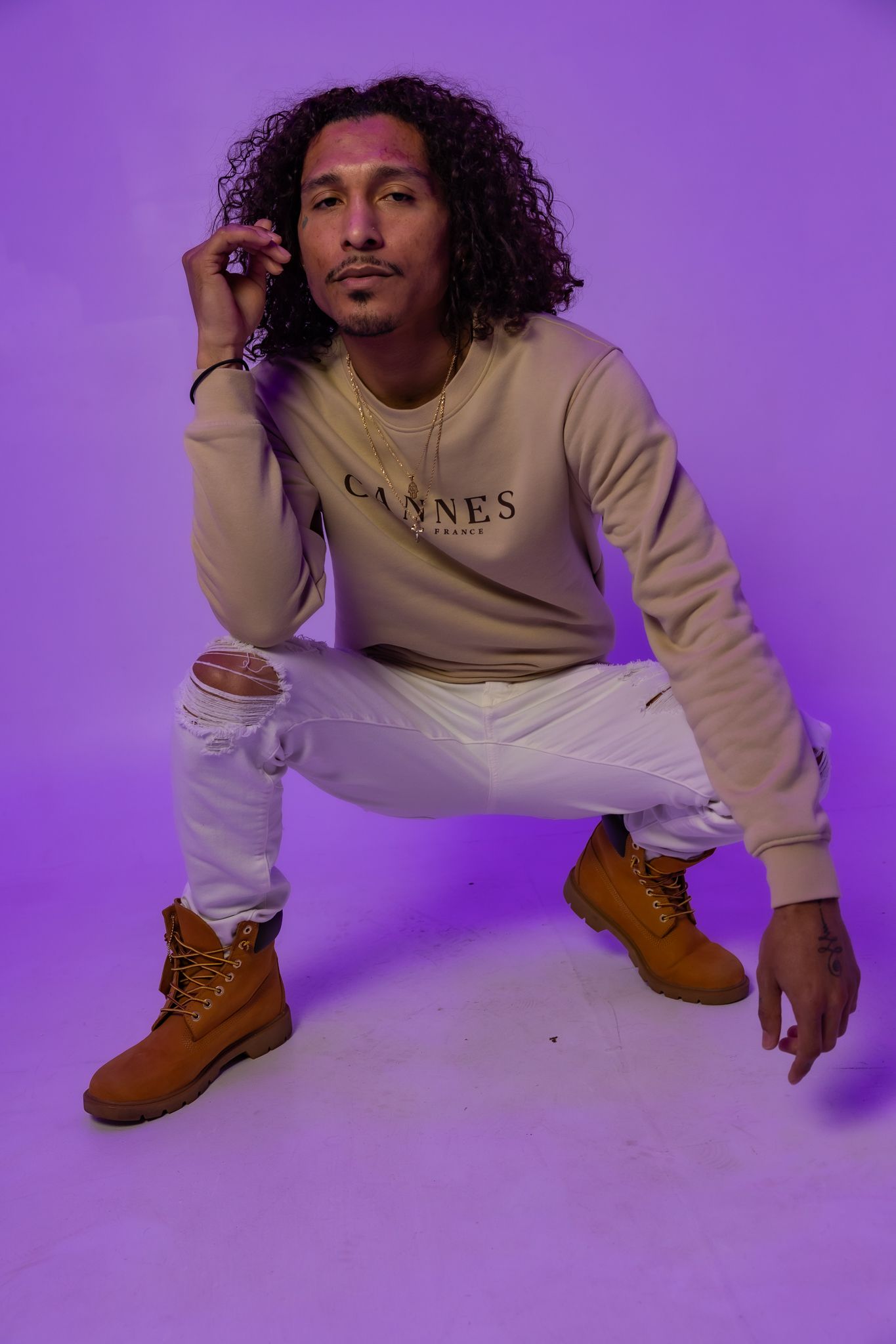 Model in casual wear strikes dynamic poses on floor with purple studio lighting.