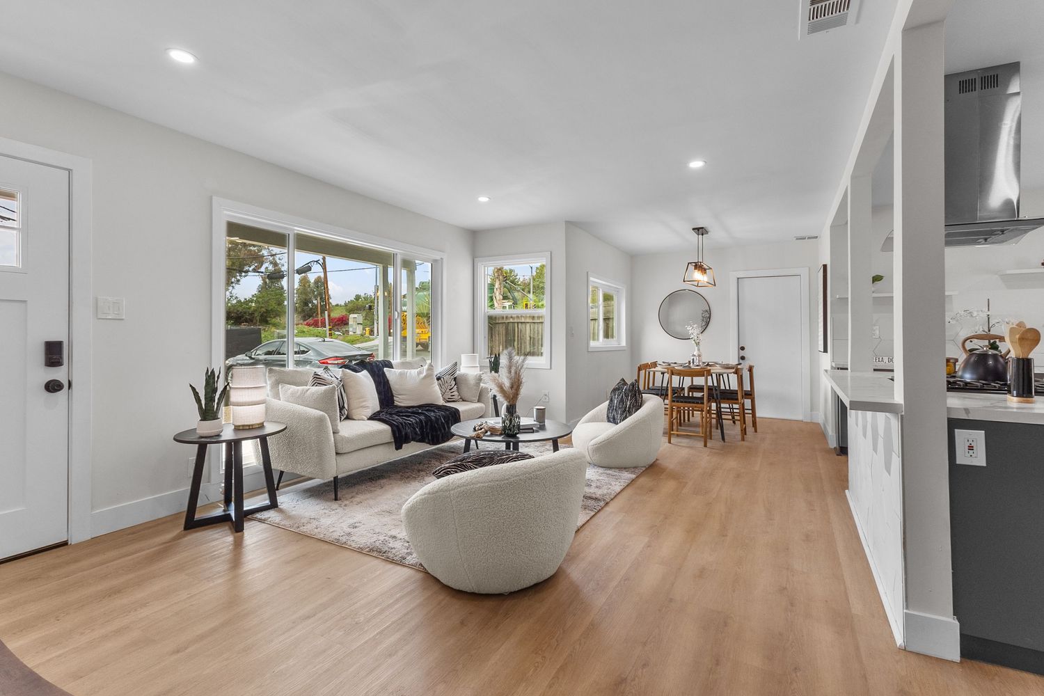 Open concept living area with white walls, wood floors and modern furnishings.