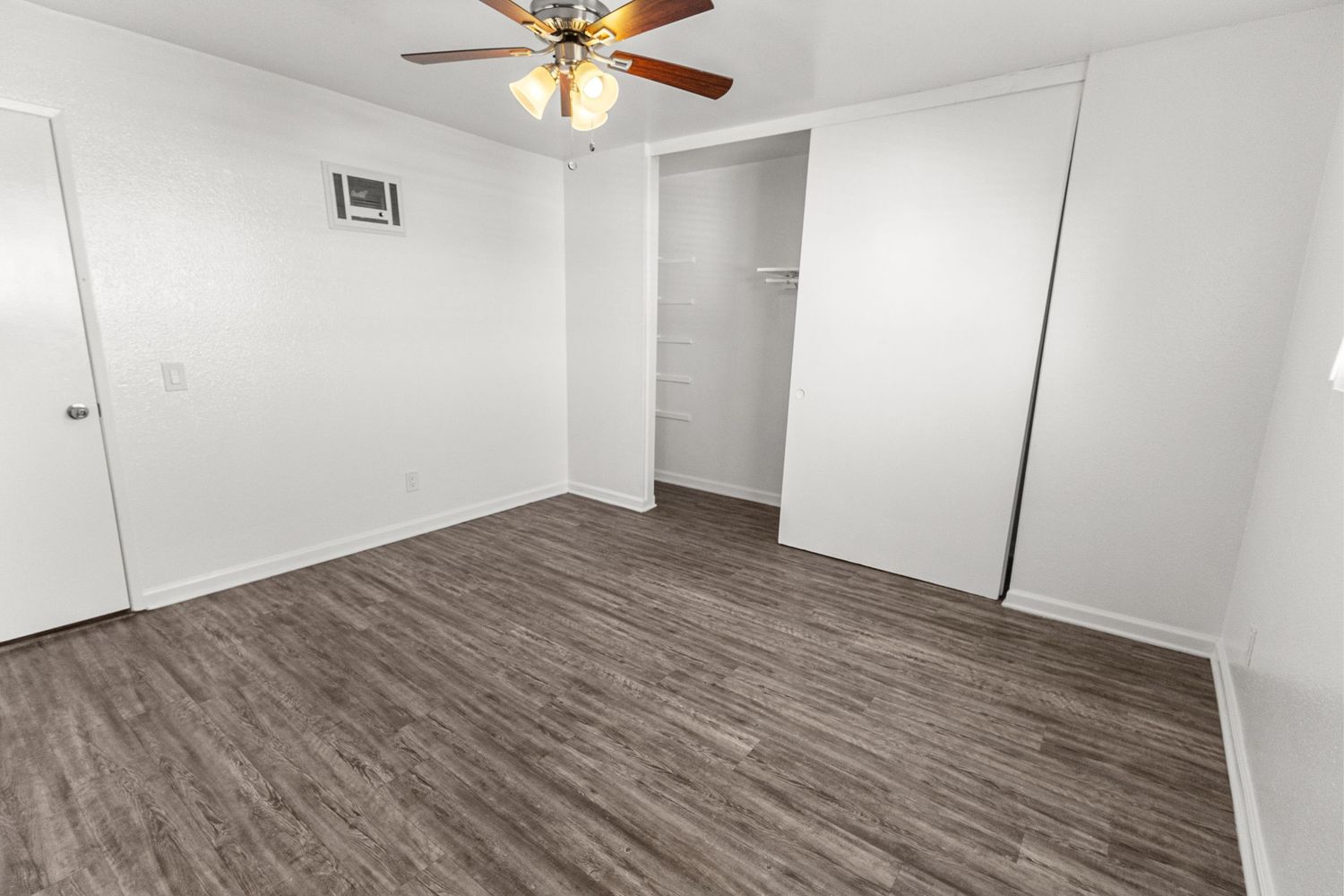 Large room with ceiling fan featuring grey vinyl flooring and white walls.