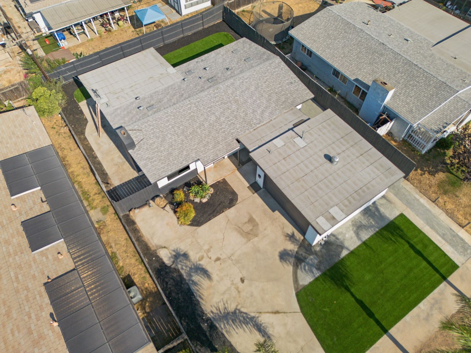 Aerial view of residential properties with driveways and yards in a suburban neighborhood.