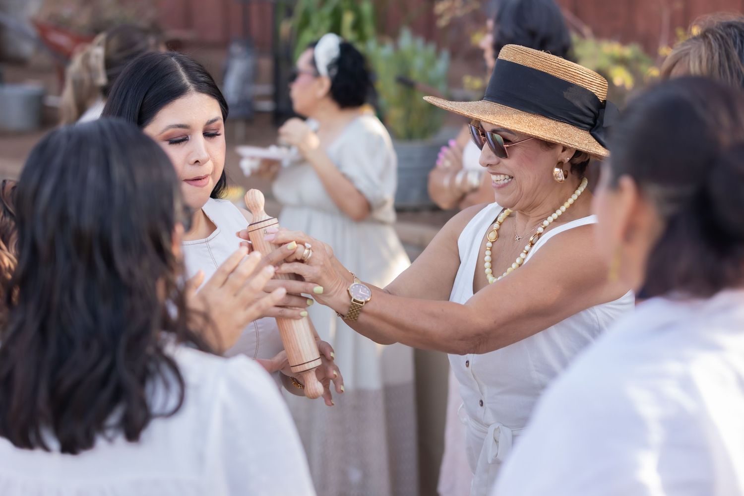 Group of people in white attire celebrating joyfully at an outdoor gathering.