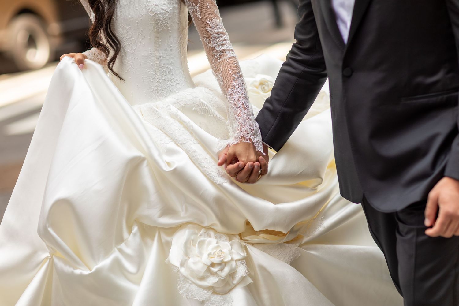 Close-up details of white wedding dress train and formal attire.
