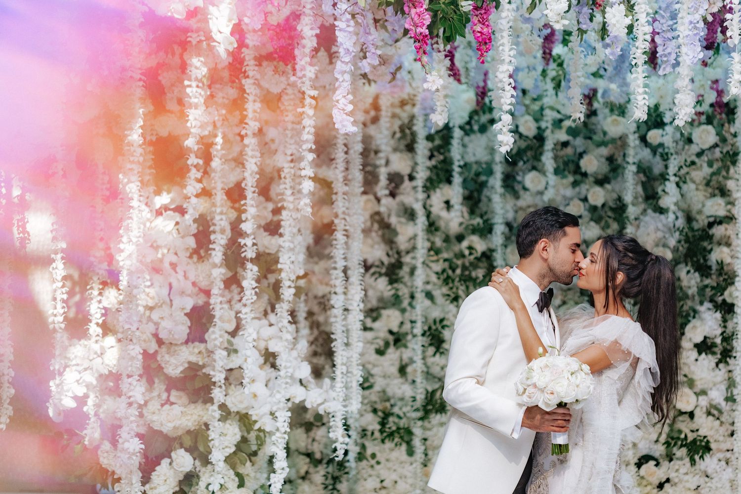 Wedding celebration under hanging crystal decorations with pink and purple lighting effects.