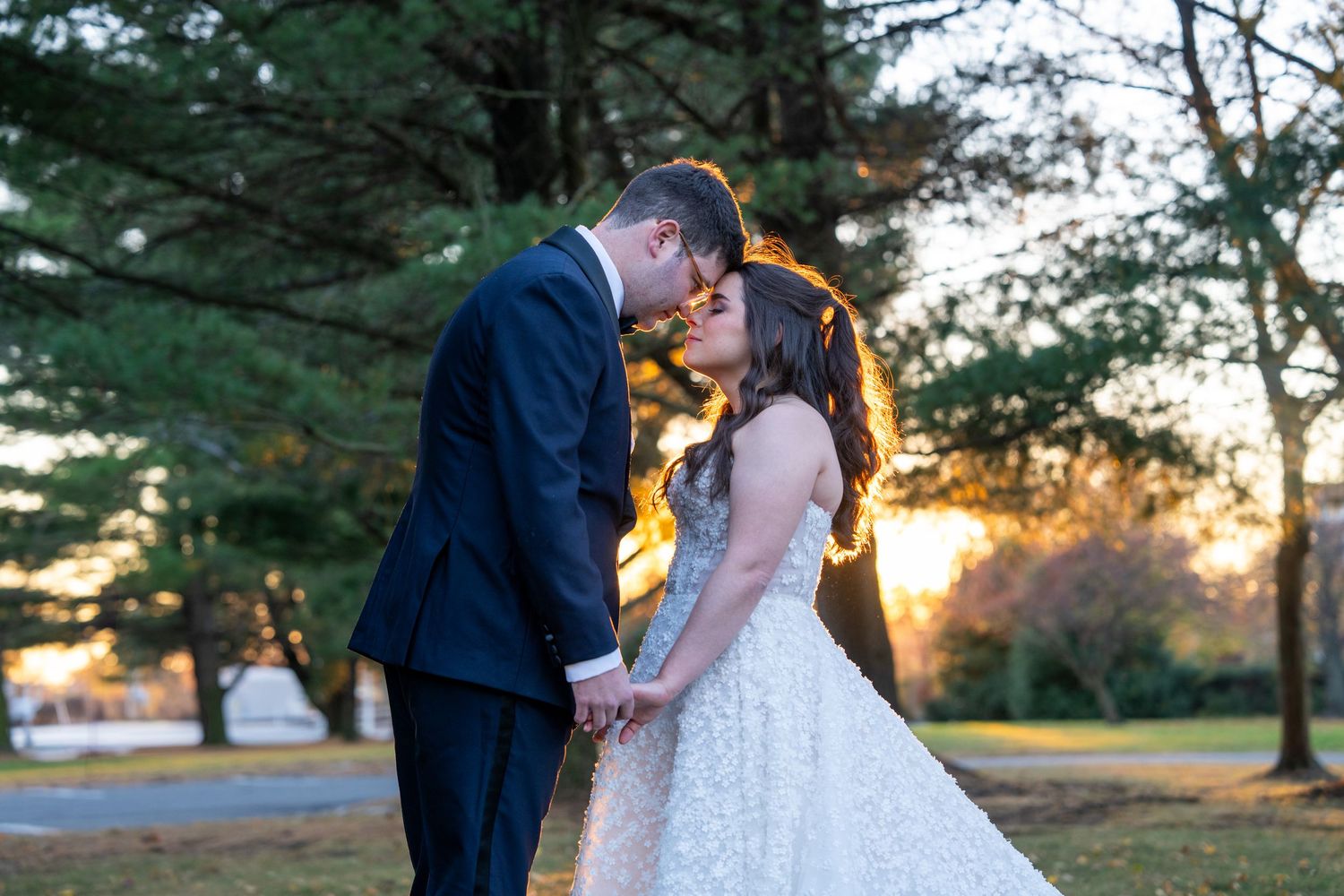 A couple shares tender moments at sunset with pine trees in the background.