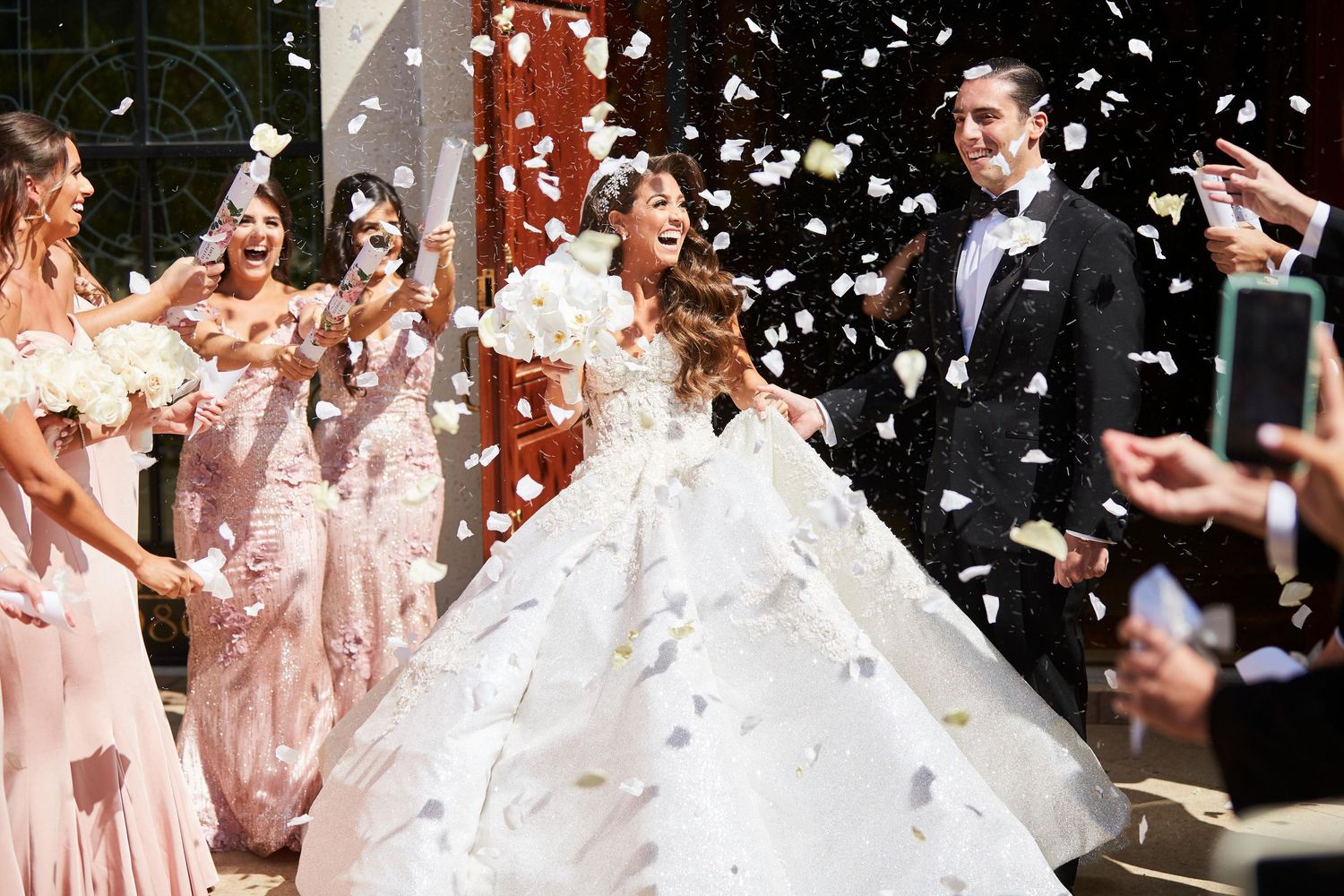 Wedding celebration with flower petals being thrown in the air during an outdoor ceremony.