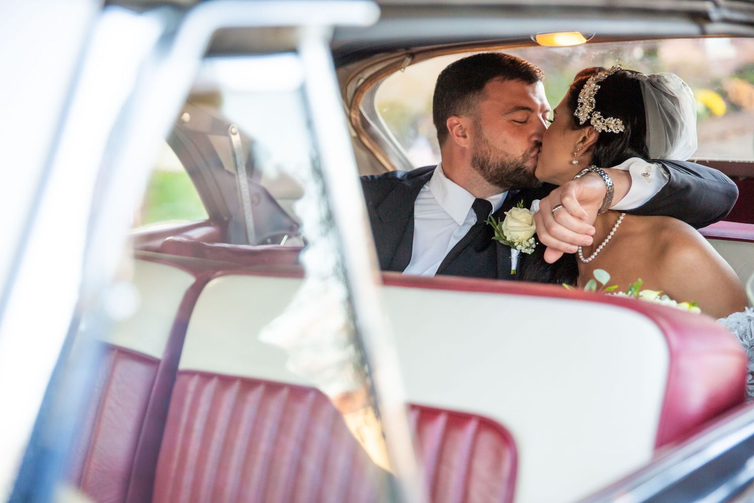 Romantic moment captured through vintage car windows during wedding celebration.