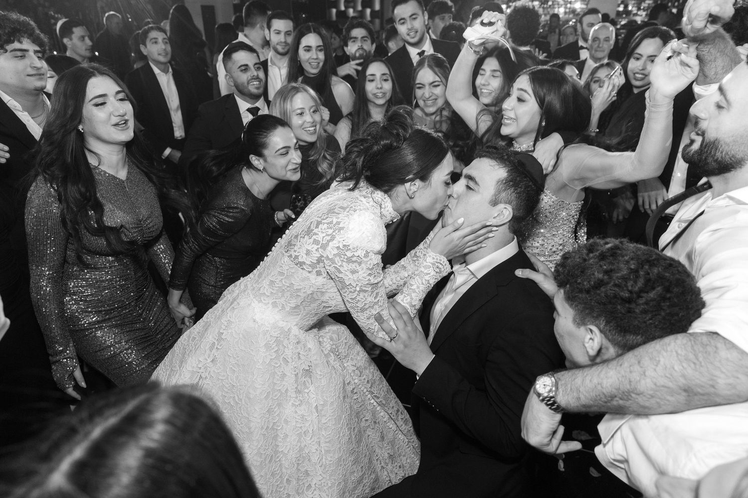 Wedding celebration captured in black and white with crowd surrounding dancing couple.