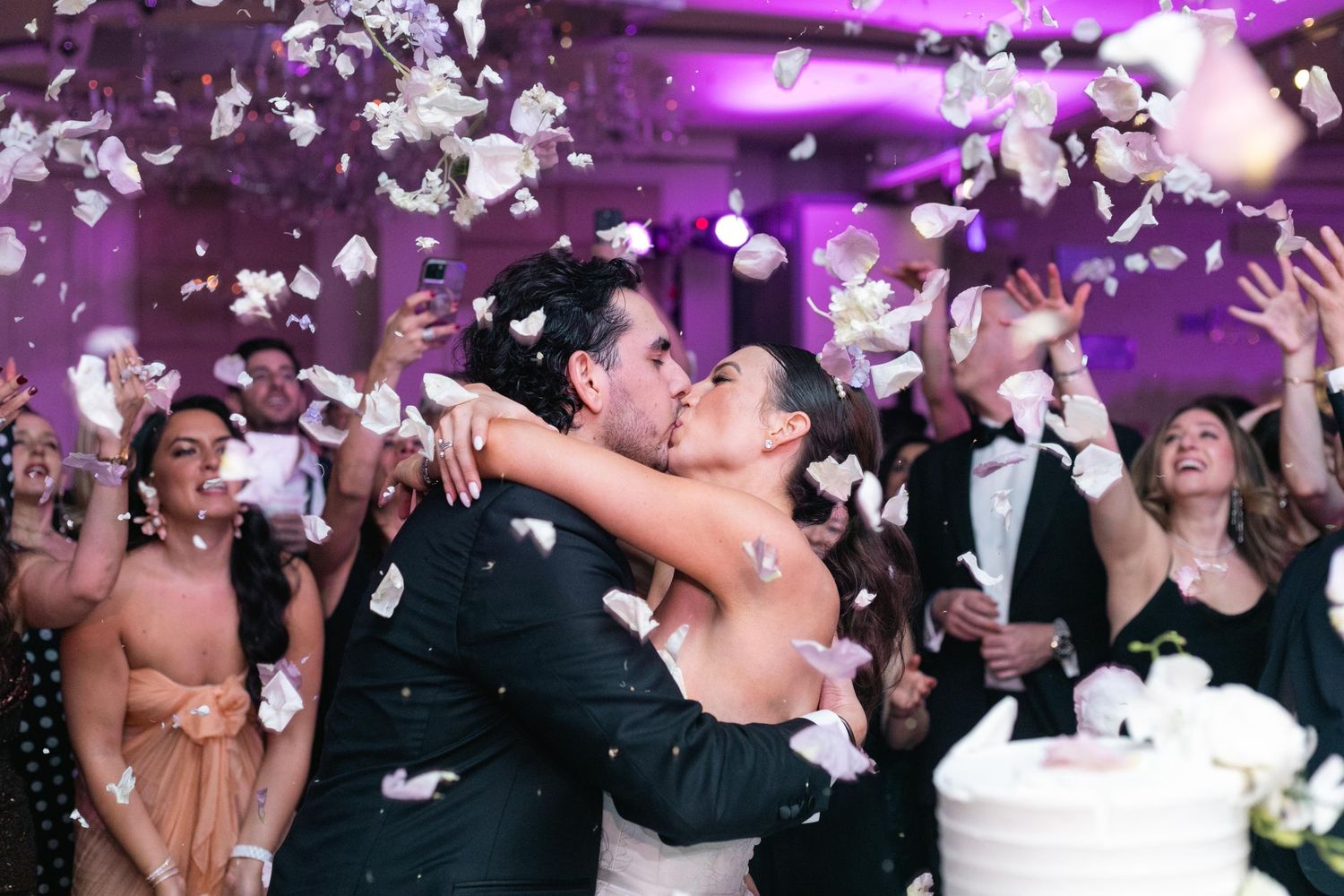 Wedding reception dance floor with purple lighting and confetti falling from above.