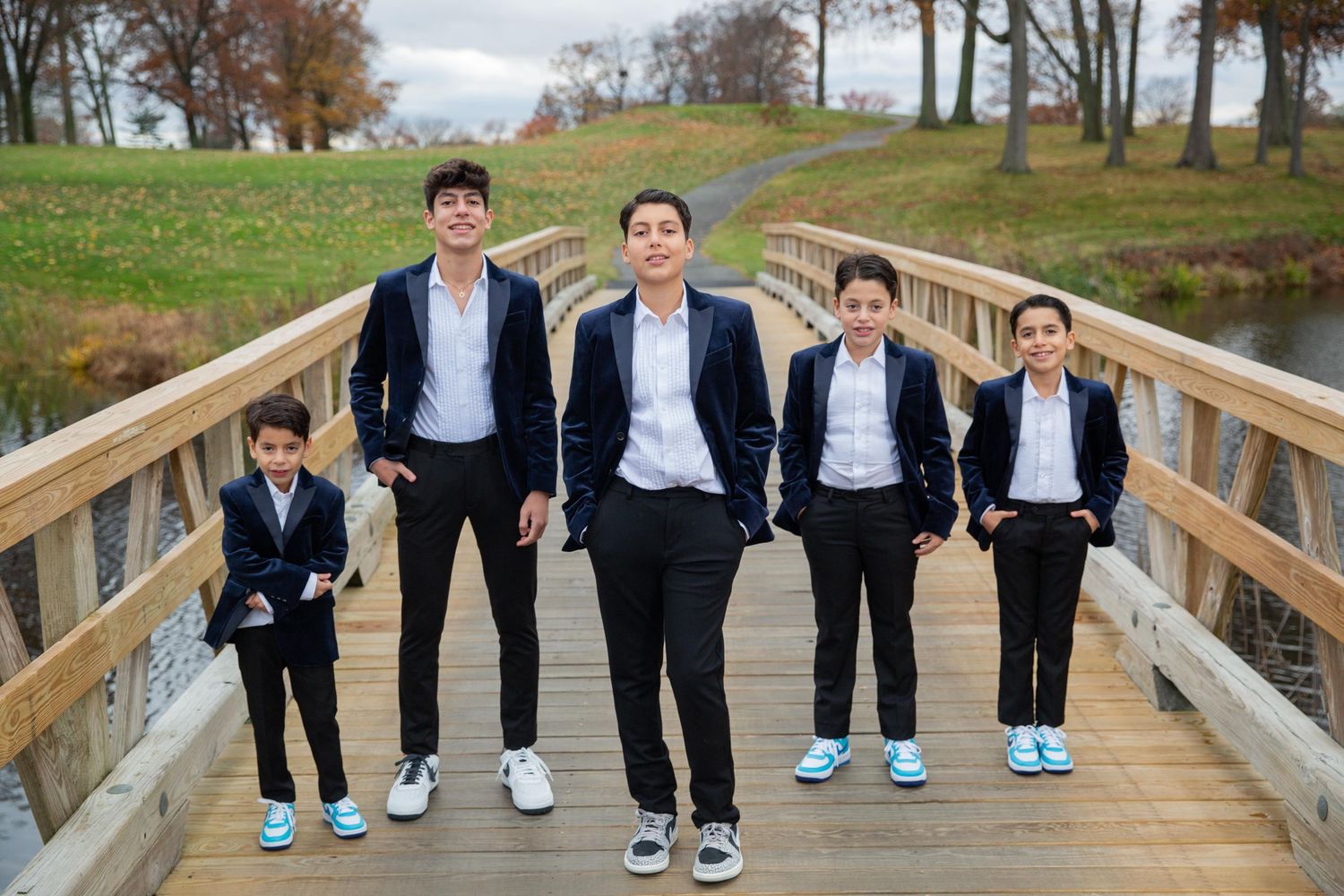 Group of young people in formal attire posing on a wooden boardwalk.