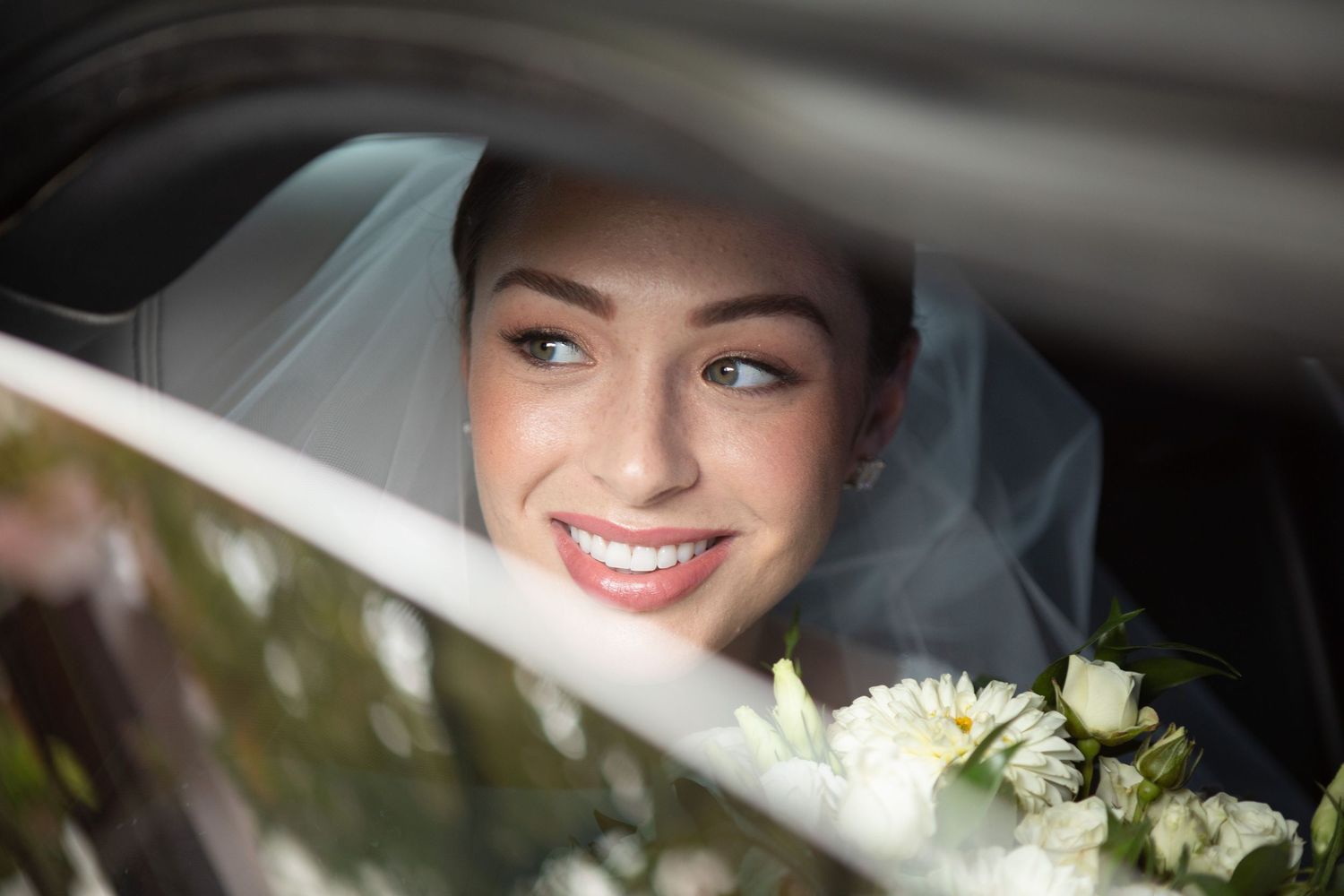 Wedding day portraits captured through a car window showing joyful moments.