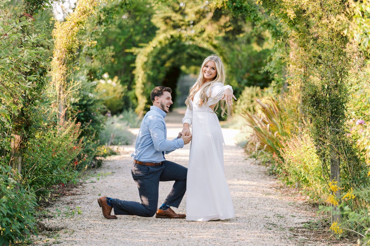 A romantic engagement photo session captured on a tree-lined path in golden sunlight.
