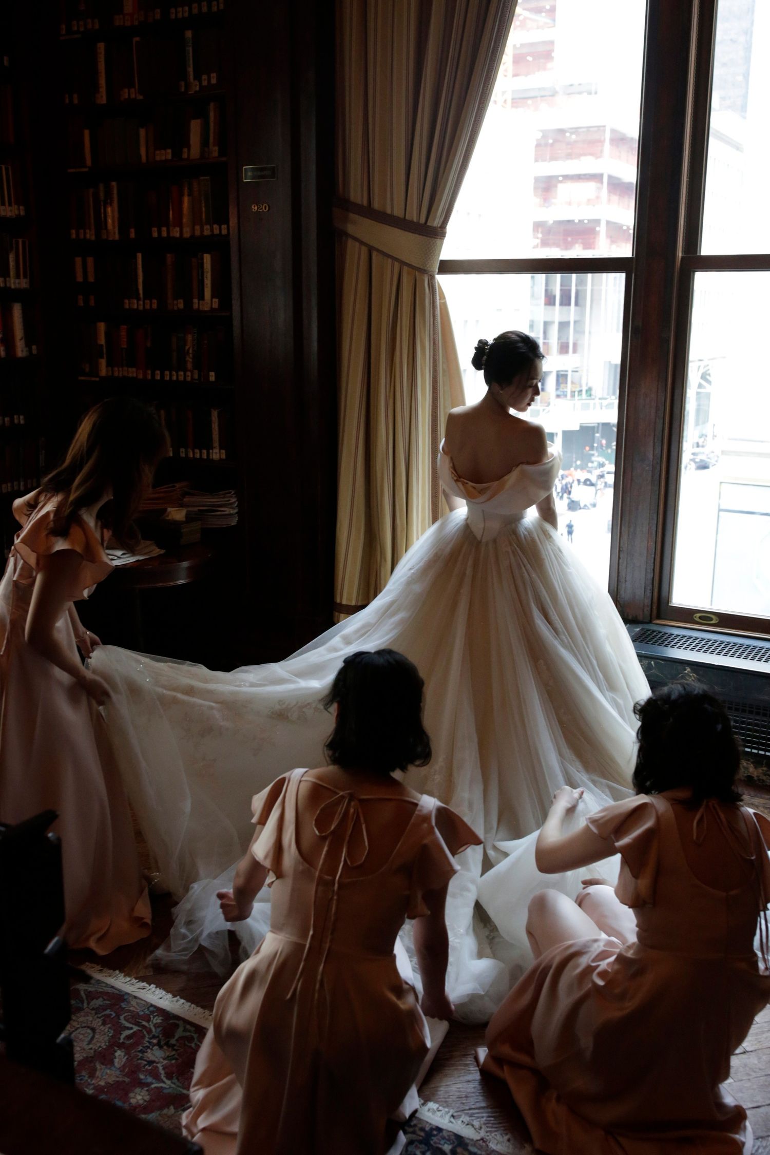 Wedding dress preparation scene in sunlit room with elegant window lighting.