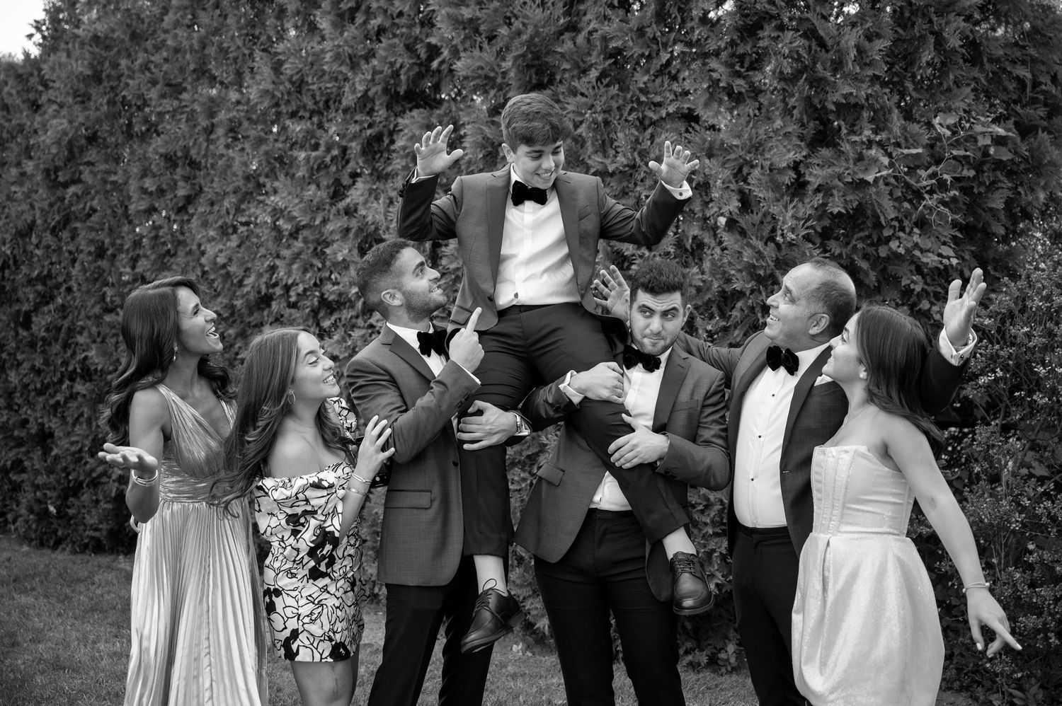 Wedding party celebrating outdoors with joyful expressions and formal attire.