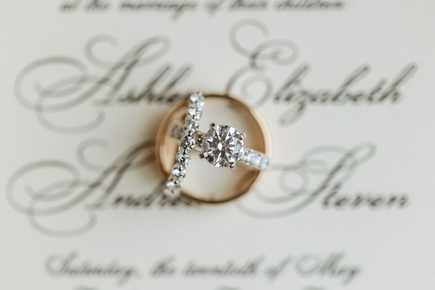 Elegant wedding rings and invitation with beautiful calligraphy details.